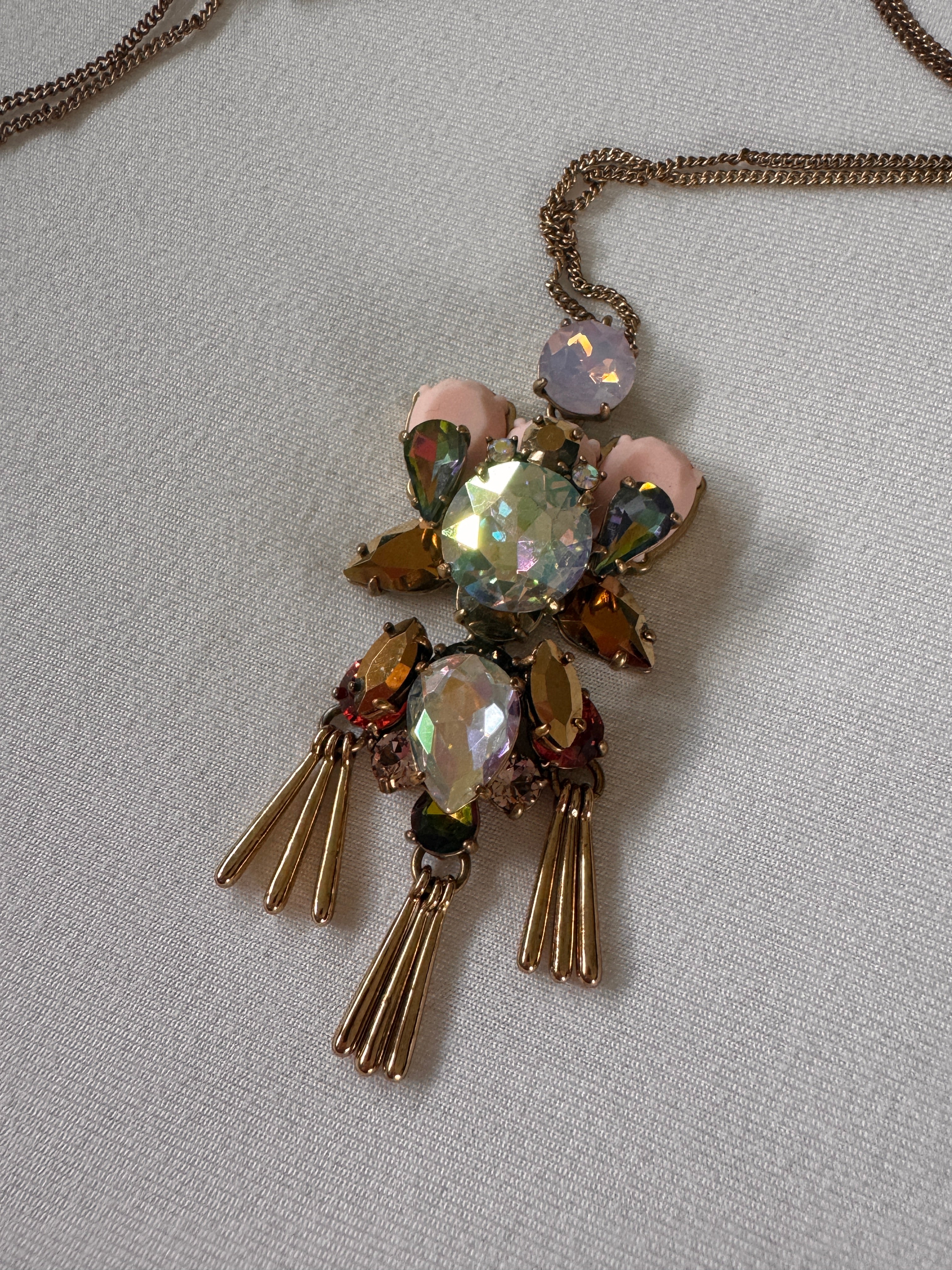 Decorative brooch style necklace with gemstones on a light gray background