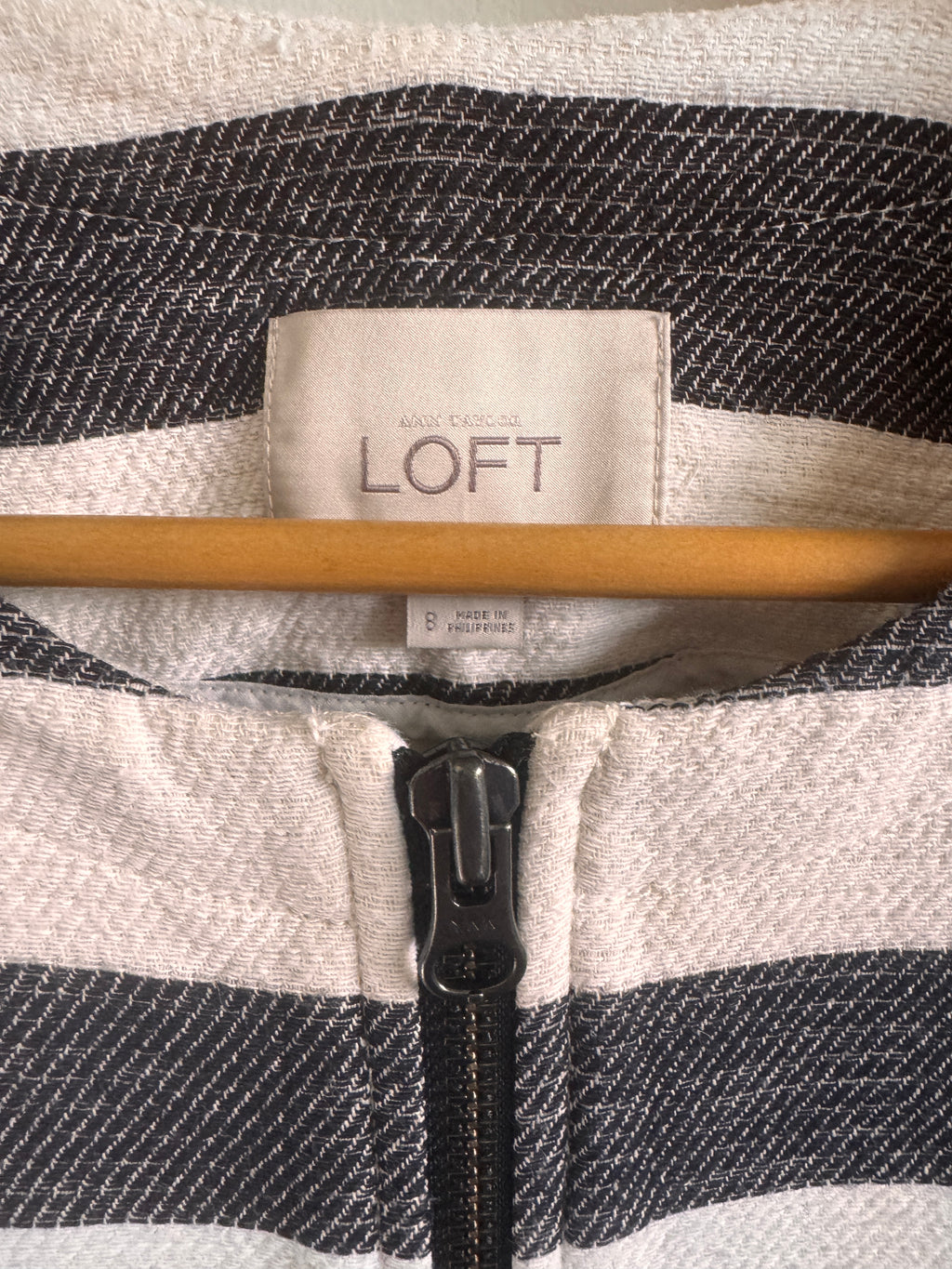 Close-up of a jacket with a LOFT label and zipper detail.