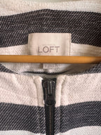 Close-up of a jacket with a LOFT label and zipper detail.