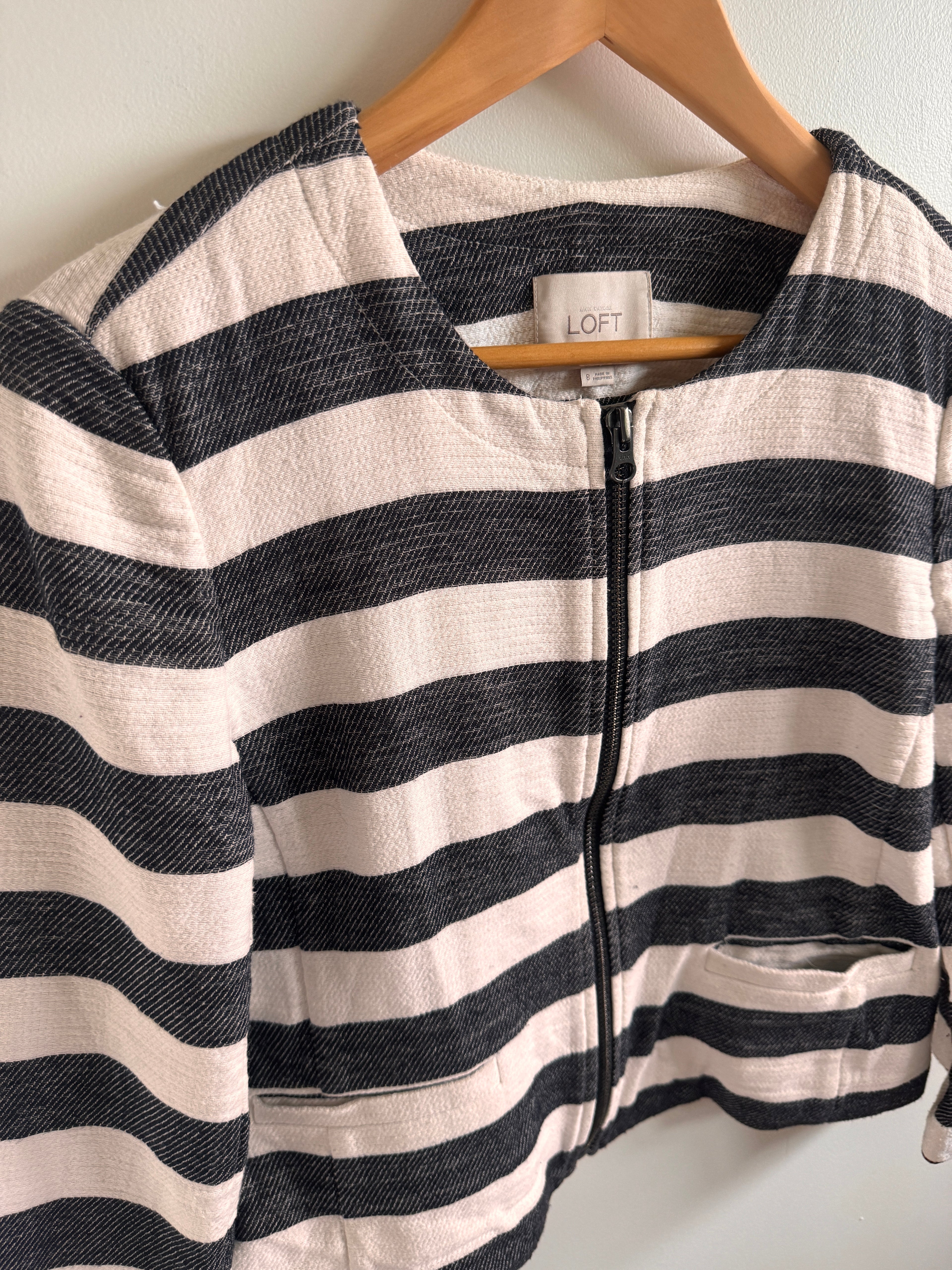 Black and white striped jacket on a hanger with a visible brand label.