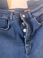 Close-up of blue denim overalls with buttons and a pocket on a light background