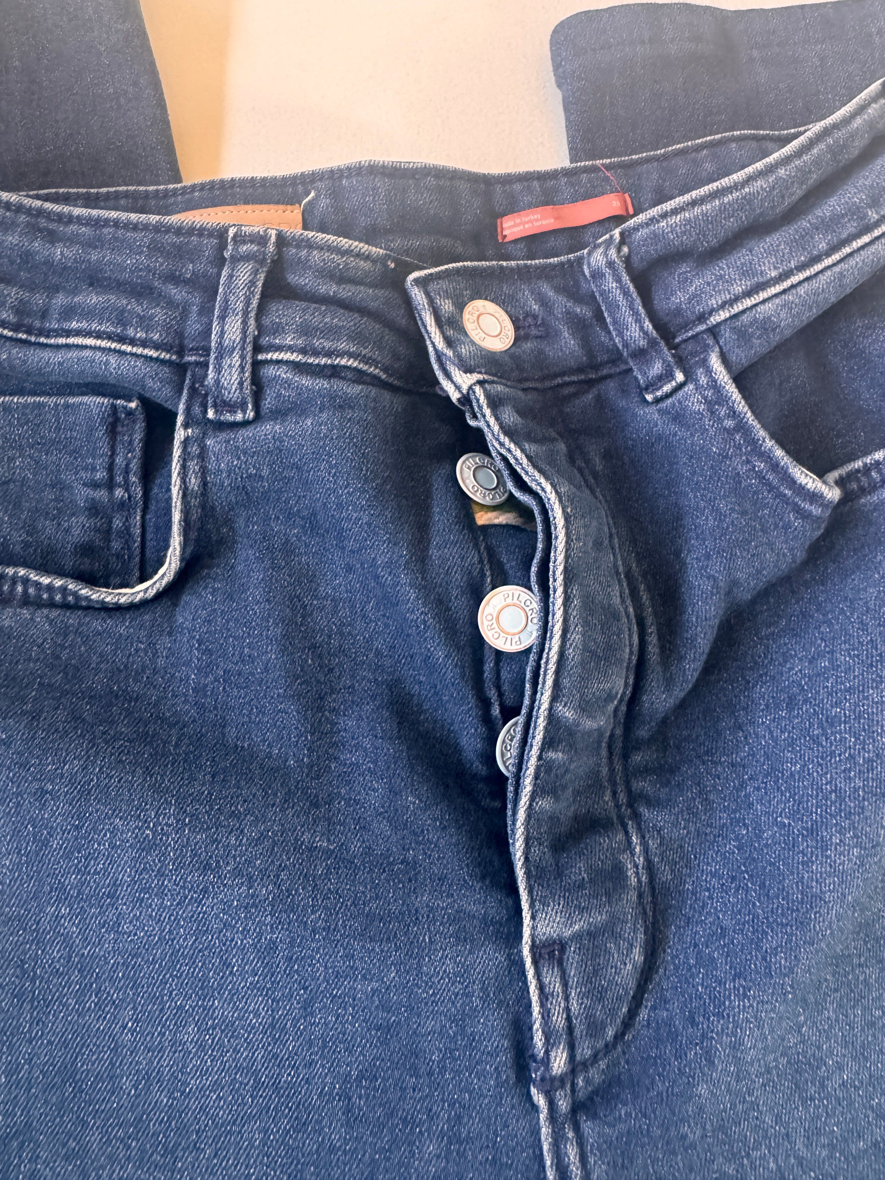 Close-up of blue denim overalls with buttons and a pocket on a light background