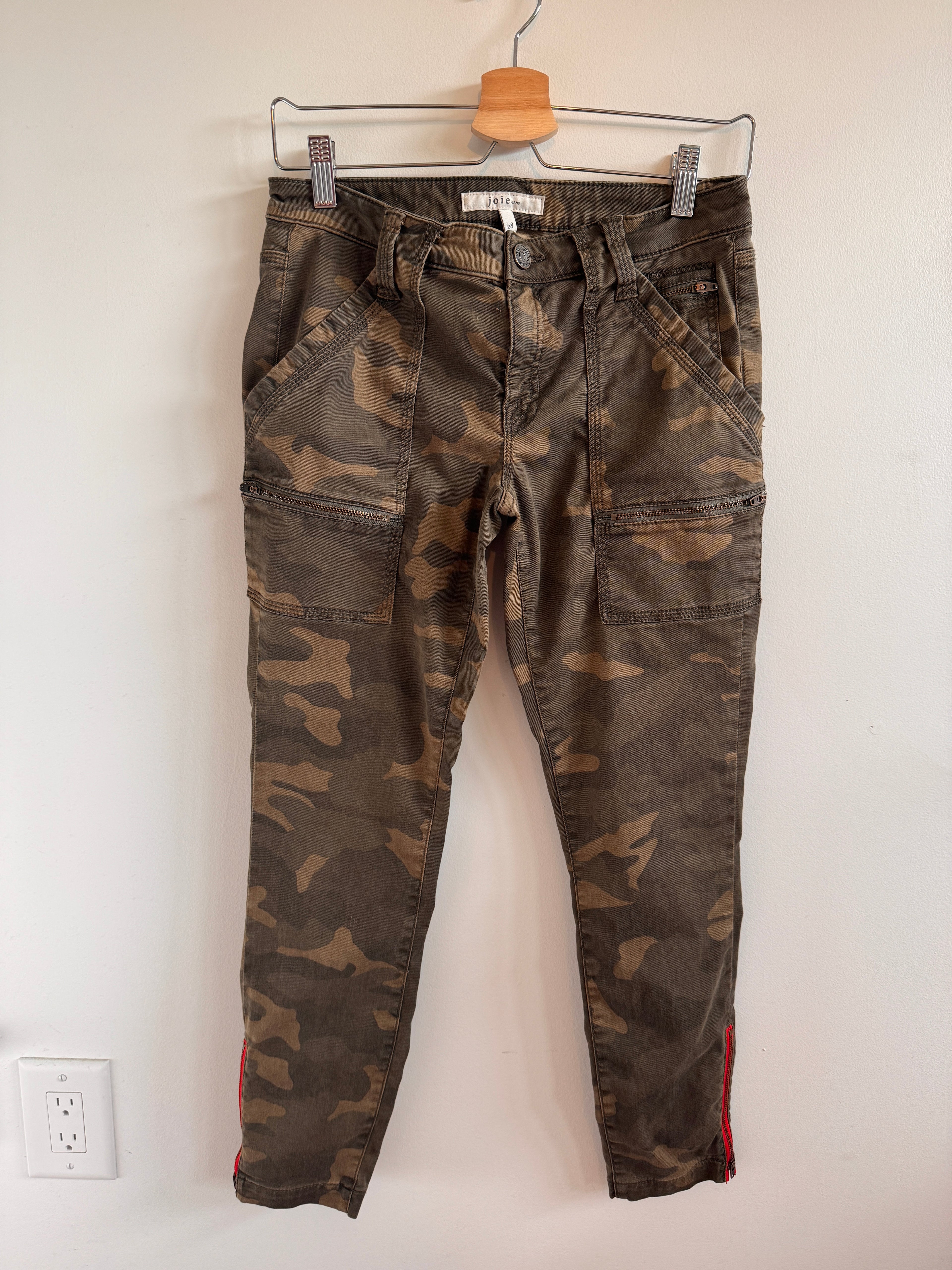 Camouflage pants on a hanger against a white wall