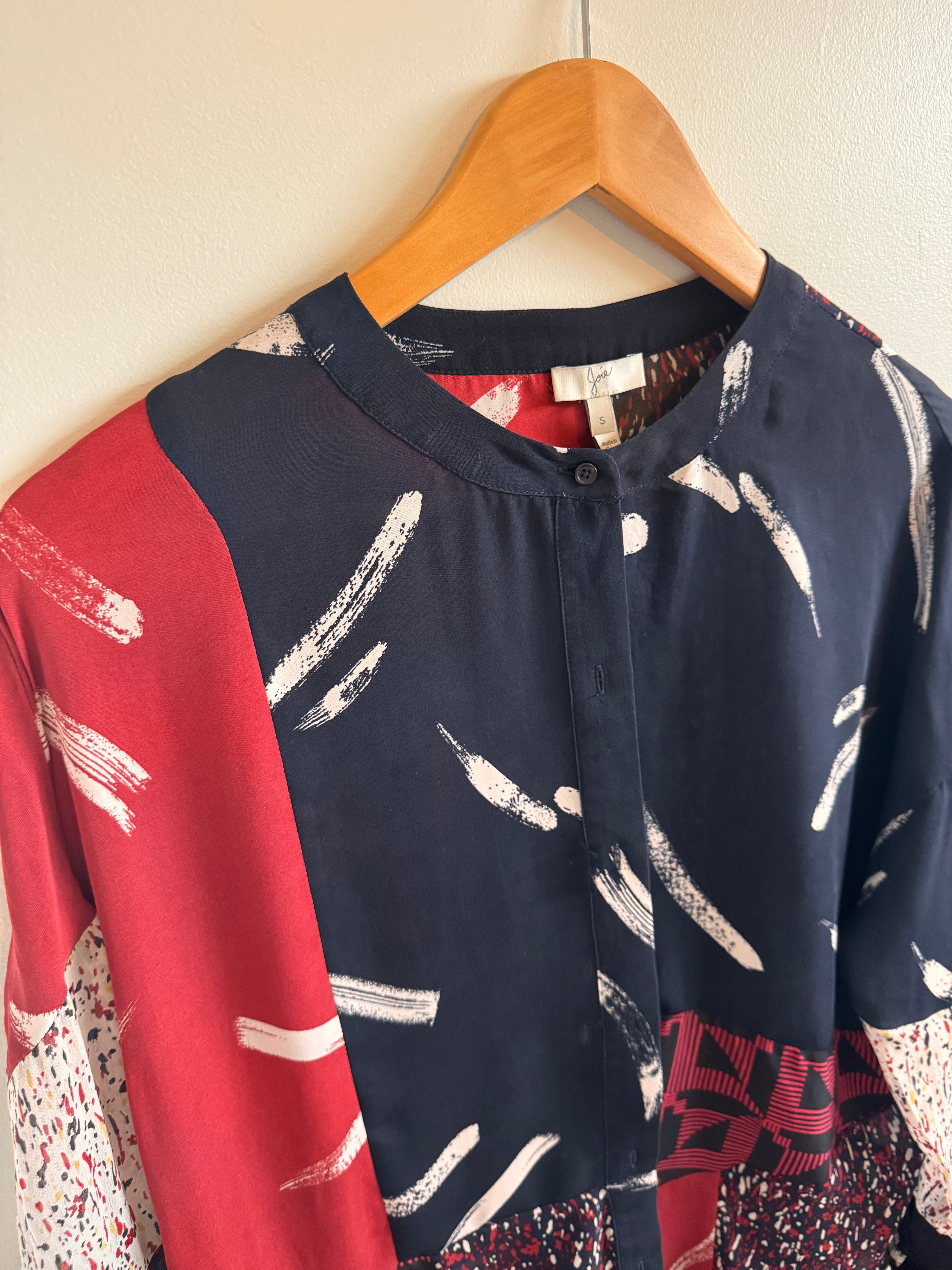 Colorful patterned shirt on a wooden hanger against a neutral background