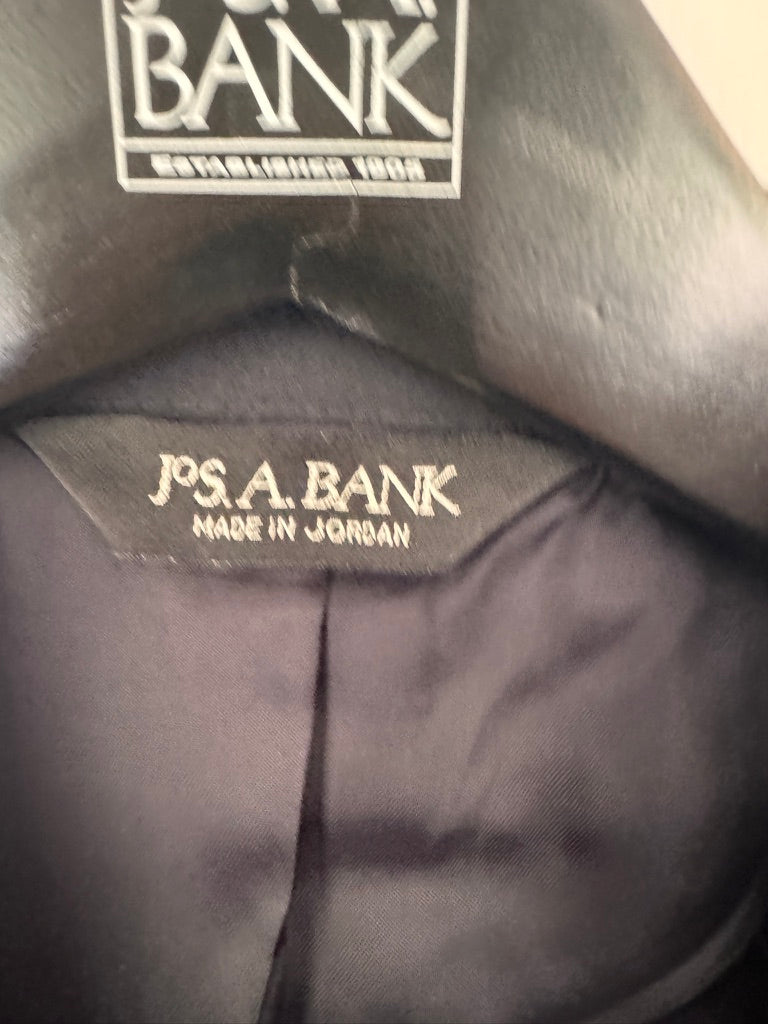Close-up of a dark gray or black garment's inner collar area showing a sewn-in label that reads 'J.P.