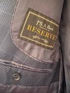 Close-up of a gray textured suit jacket lining with a sewn-in patch reading 'J'S. A.