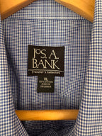 Close-up of the inside collar of a blue and white gingham shirt on a wooden hanger, showing the Jos. A. Bank brand label.