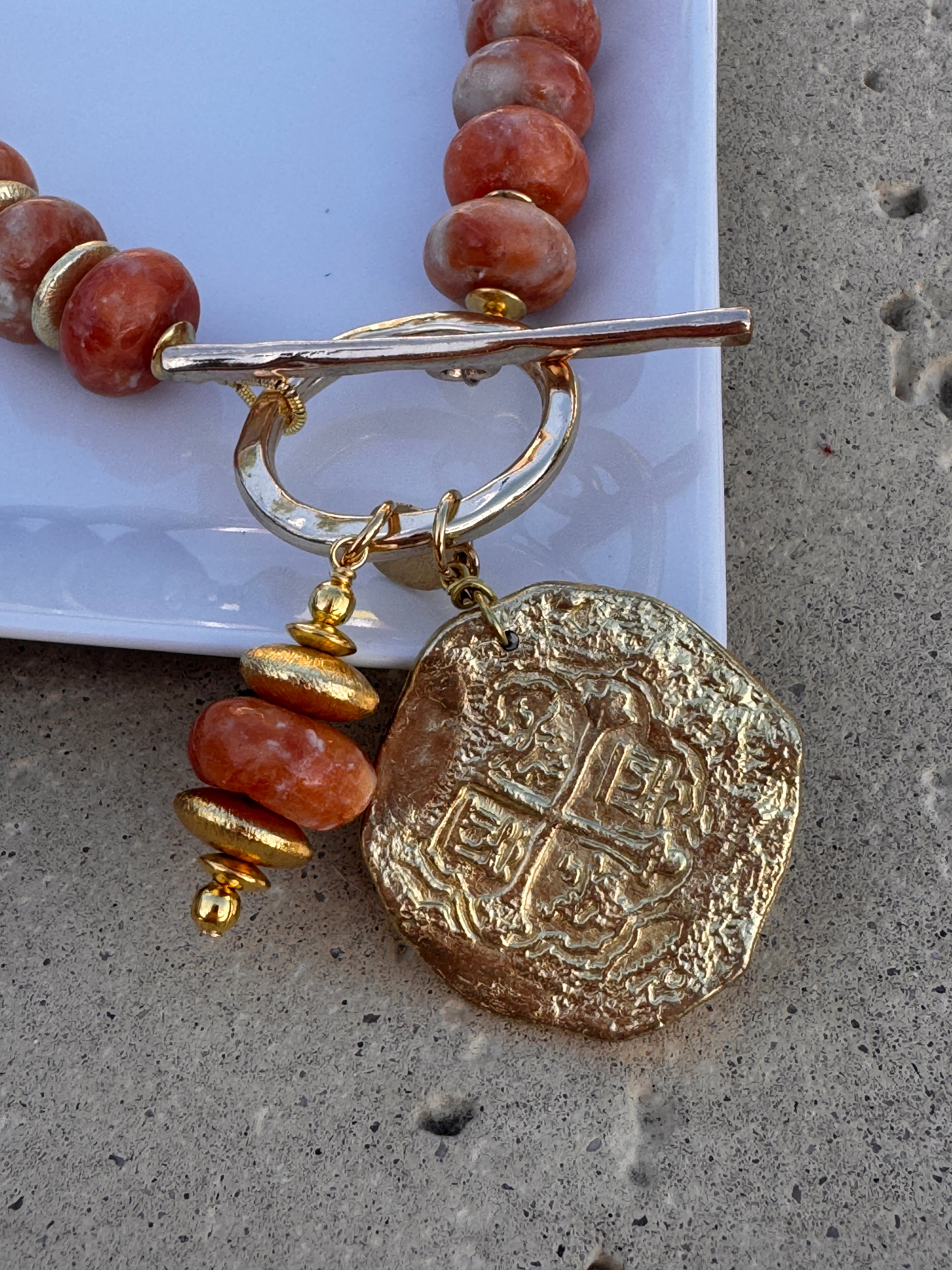 Necklace with gold and red beads on a textured surface