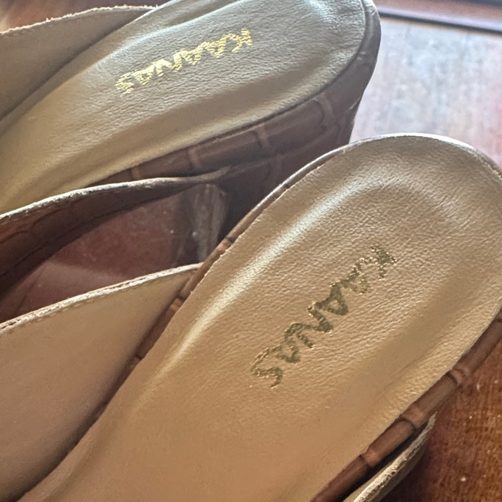 Close-up of the upper of a pair of sandals with 'KAANAS' branding on a wooden surface.