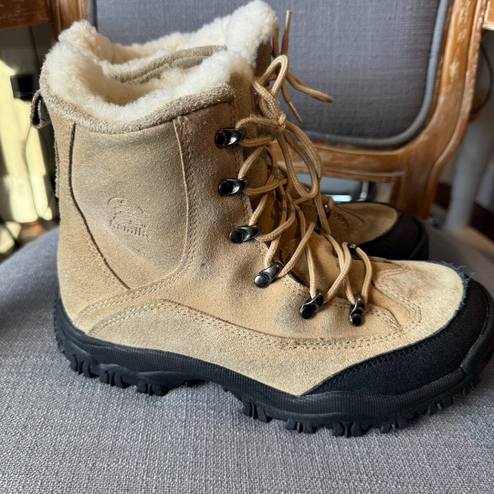 Pair of brown winter boots with black soles on a gray surface.