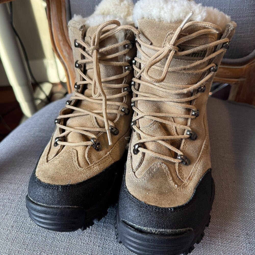 Pair of tan hiking boots with black soles on a gray surface