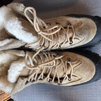 Pair of beige hiking boots with laces on a gray surface