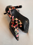 Black high-heeled shoes with floral pattern on a light background