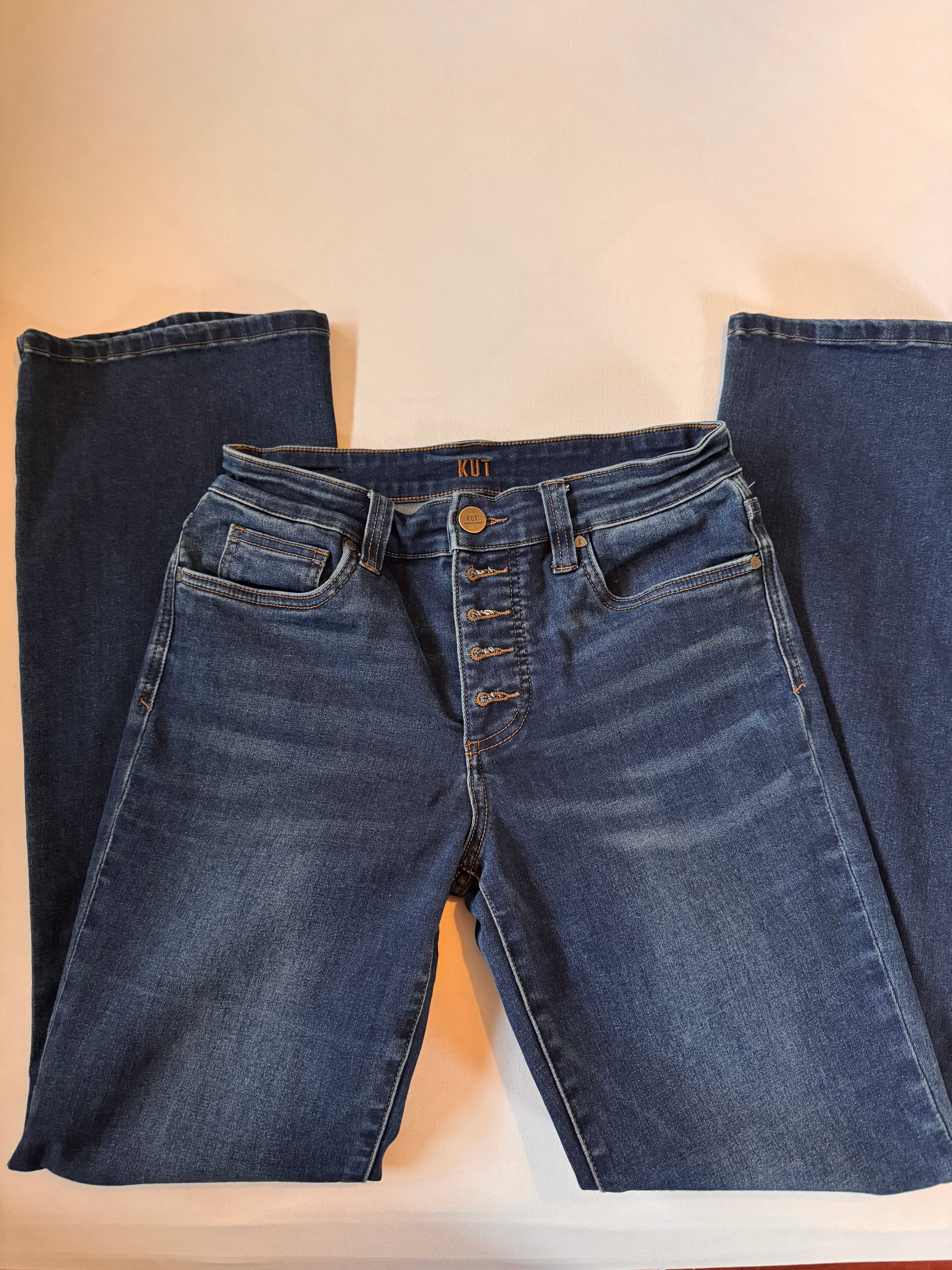 Folded pair of blue jeans on a beige surface