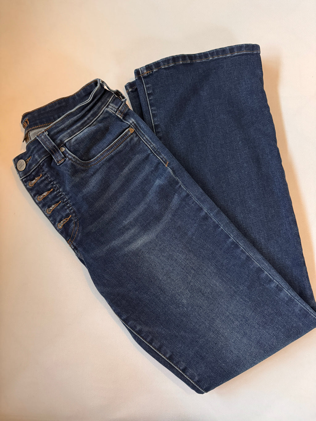 Folded pair of blue jeans on a beige background