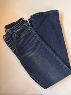 Folded pair of blue jeans on a beige background