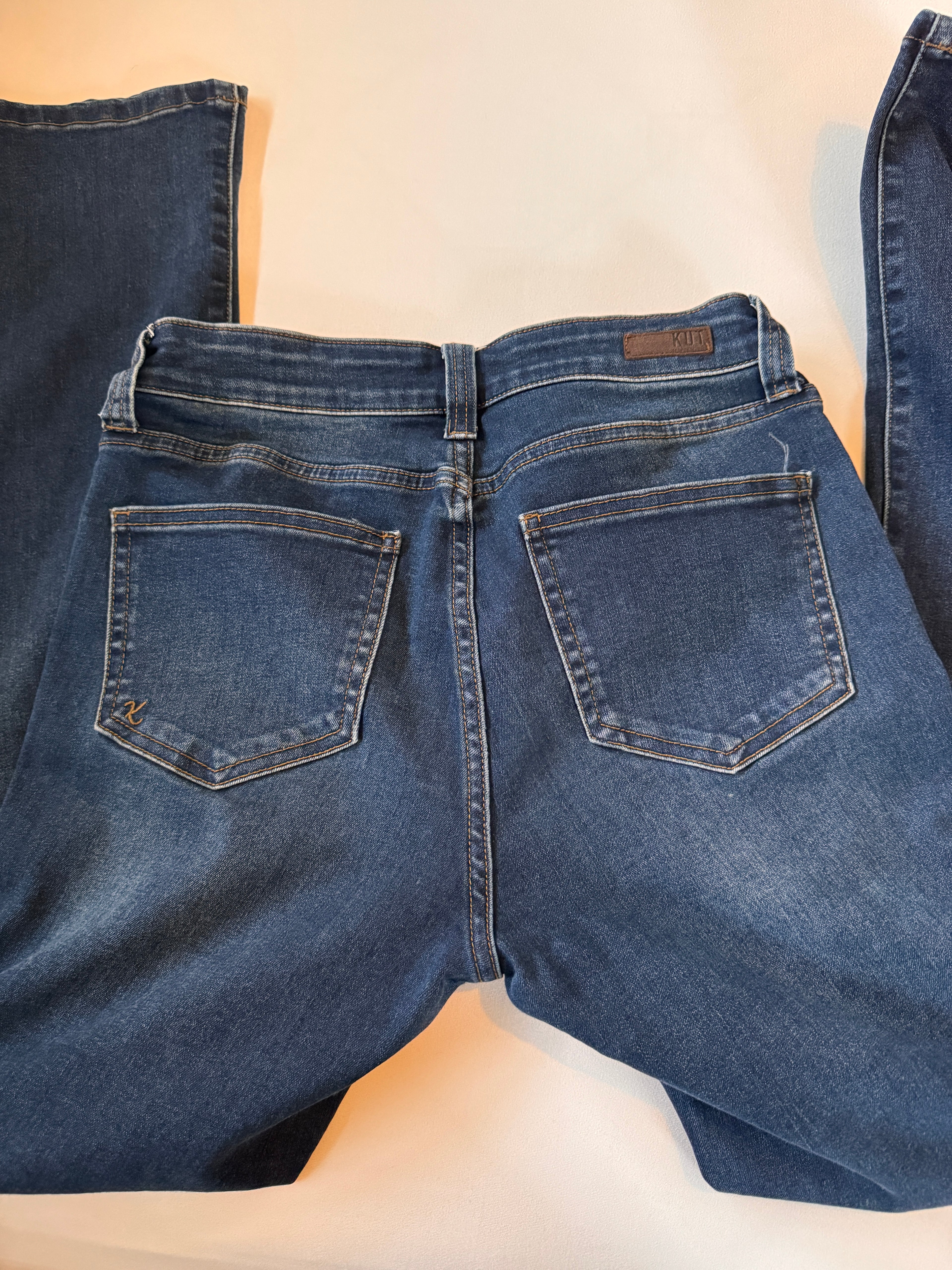 Pair of blue jeans laid flat on a beige surface