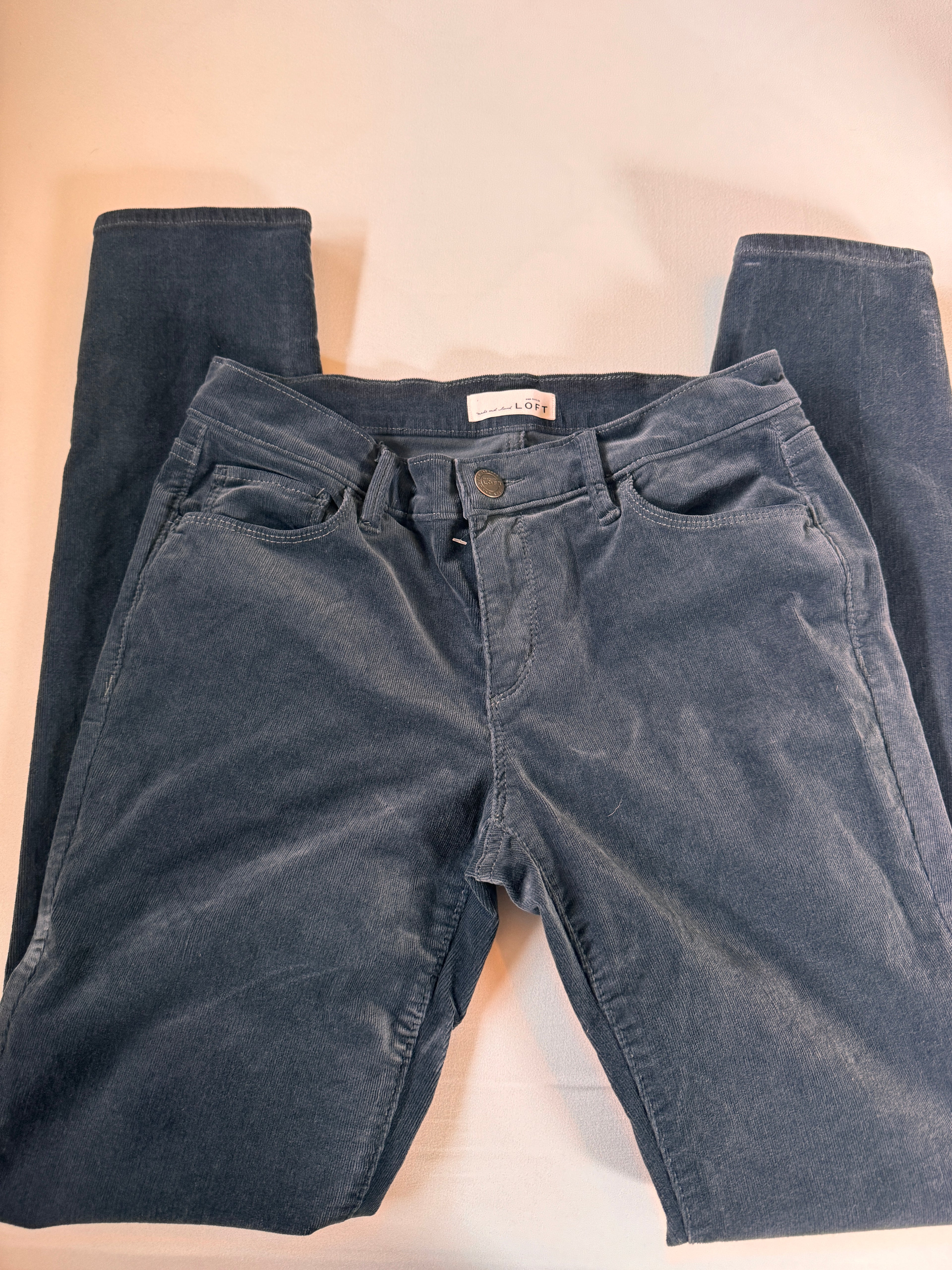 Folded pair of dark blue jeans on a light beige surface