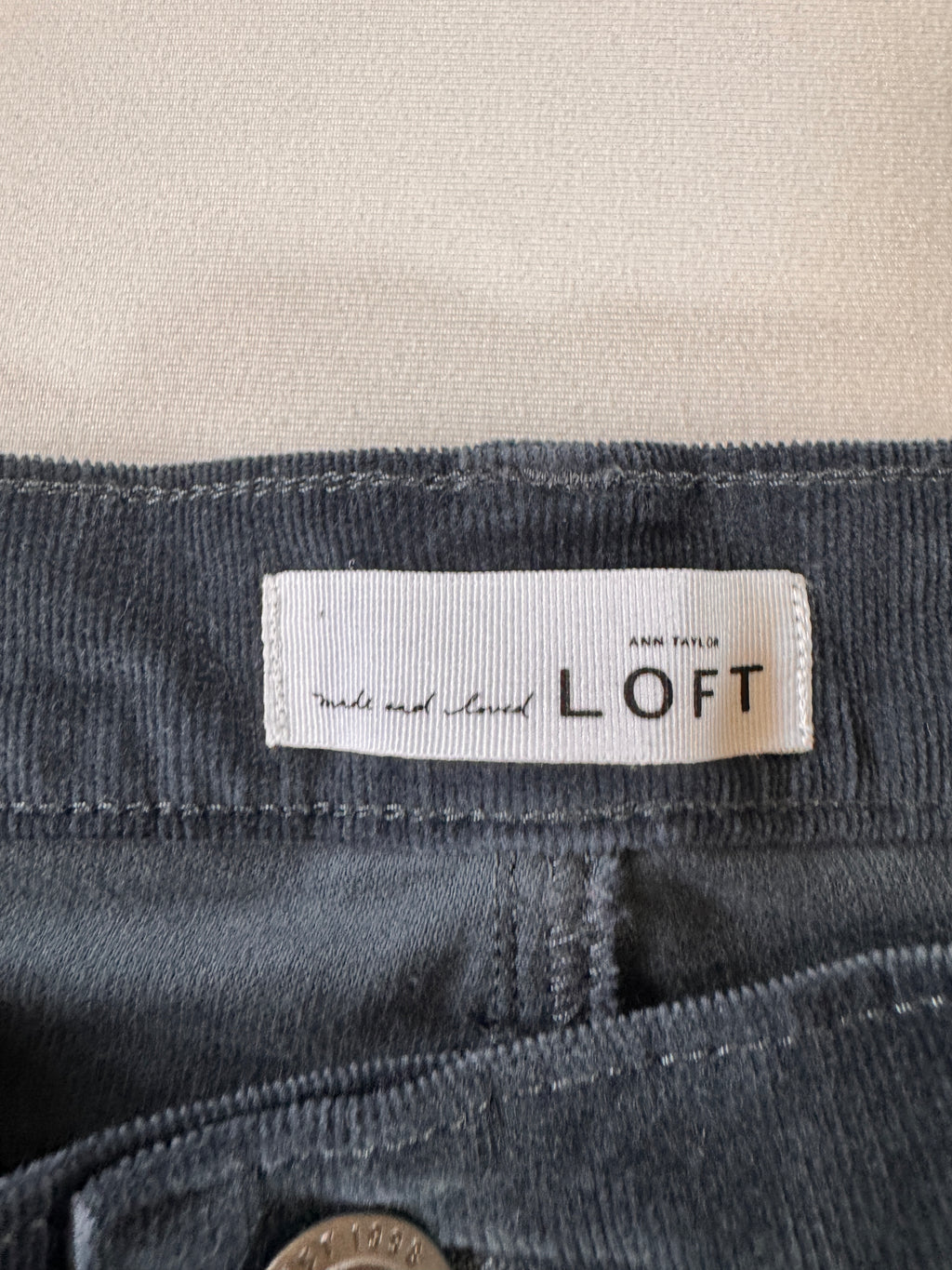 Close-up of a 'LOFT' label on a dark gray fabric background