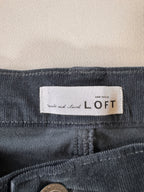 Close-up of a 'LOFT' label on a dark gray fabric background
