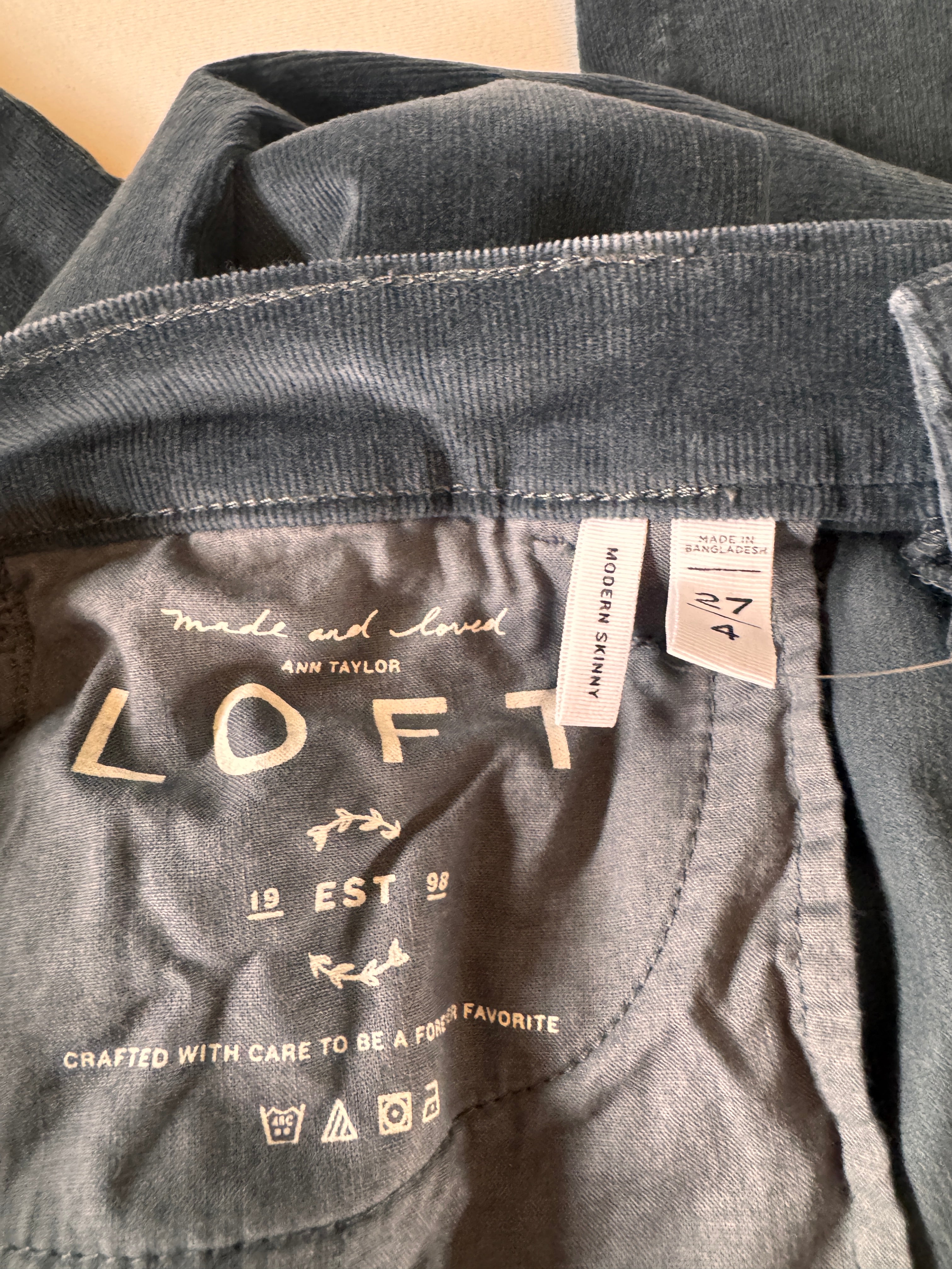 Close-up of gray pants with 'Loft' branding and labels.