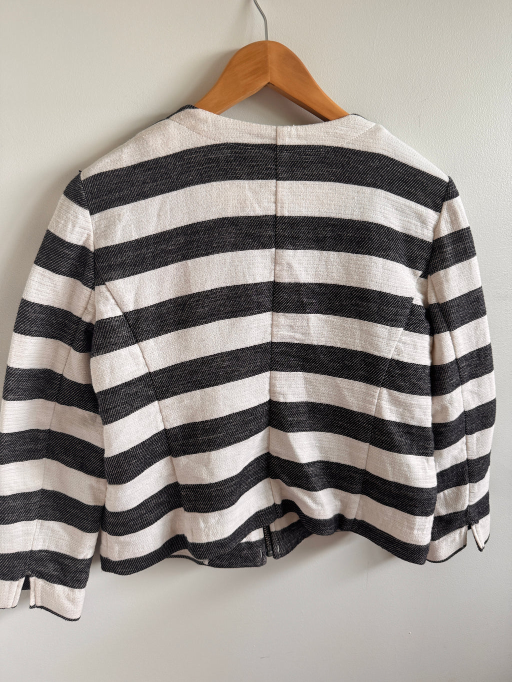 Black and white striped garment on a wooden hanger against a light gray background