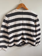 Black and white striped garment on a wooden hanger against a light gray background