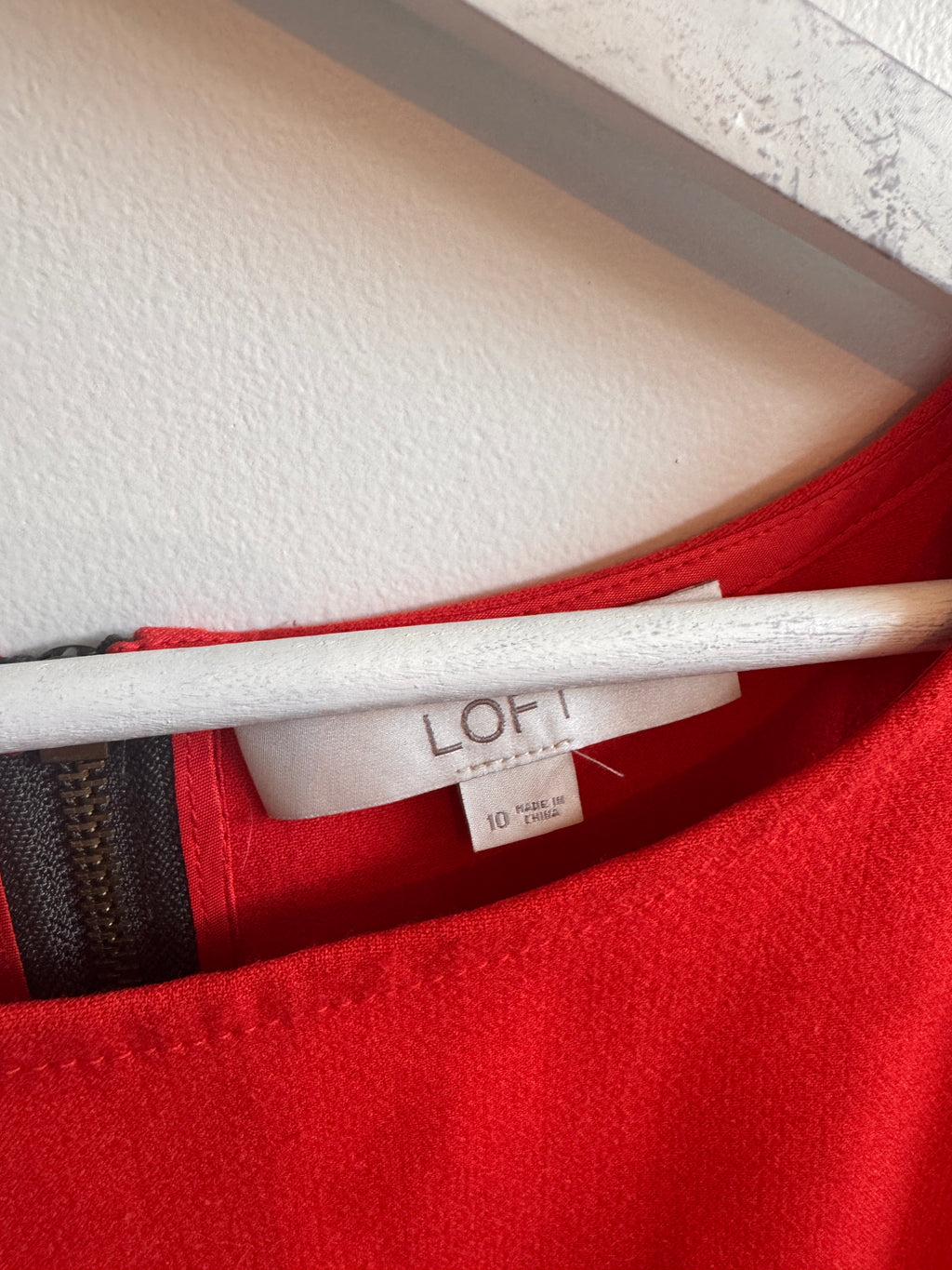 Close-up of a red garment with a white label inside, on a textured surface.
