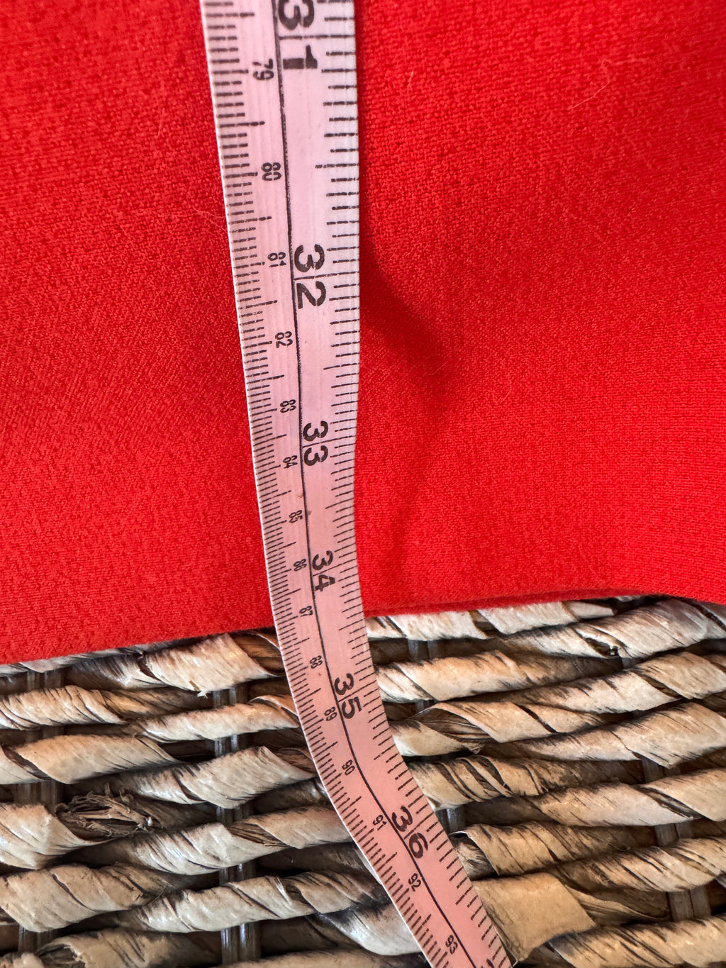 Measuring tape on a red fabric background with coiled rope