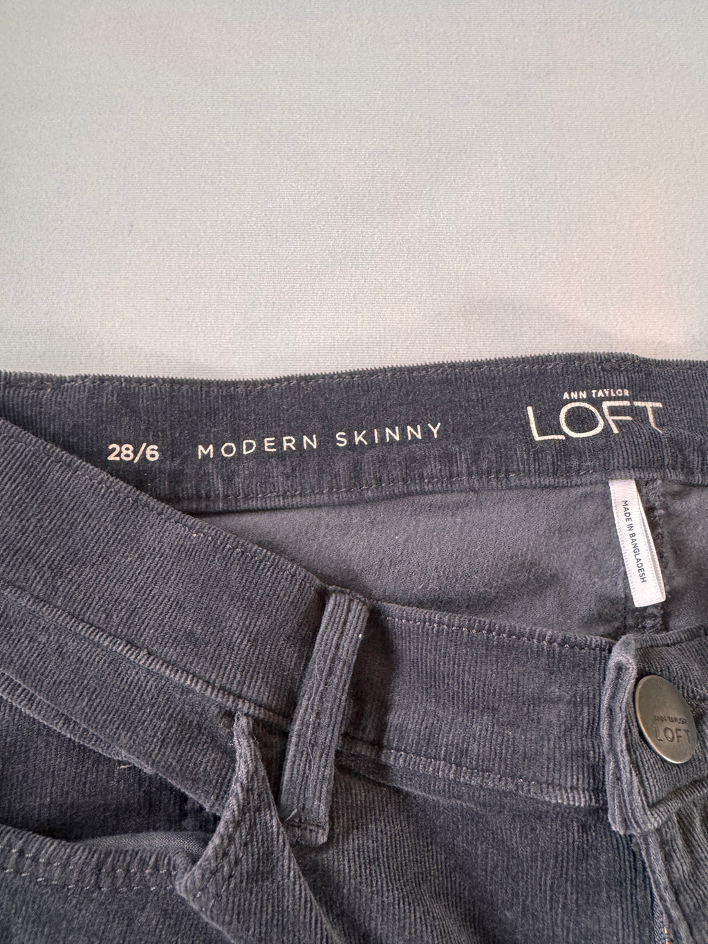 Gray jeans with 'Loft' branding and size information on a light gray background