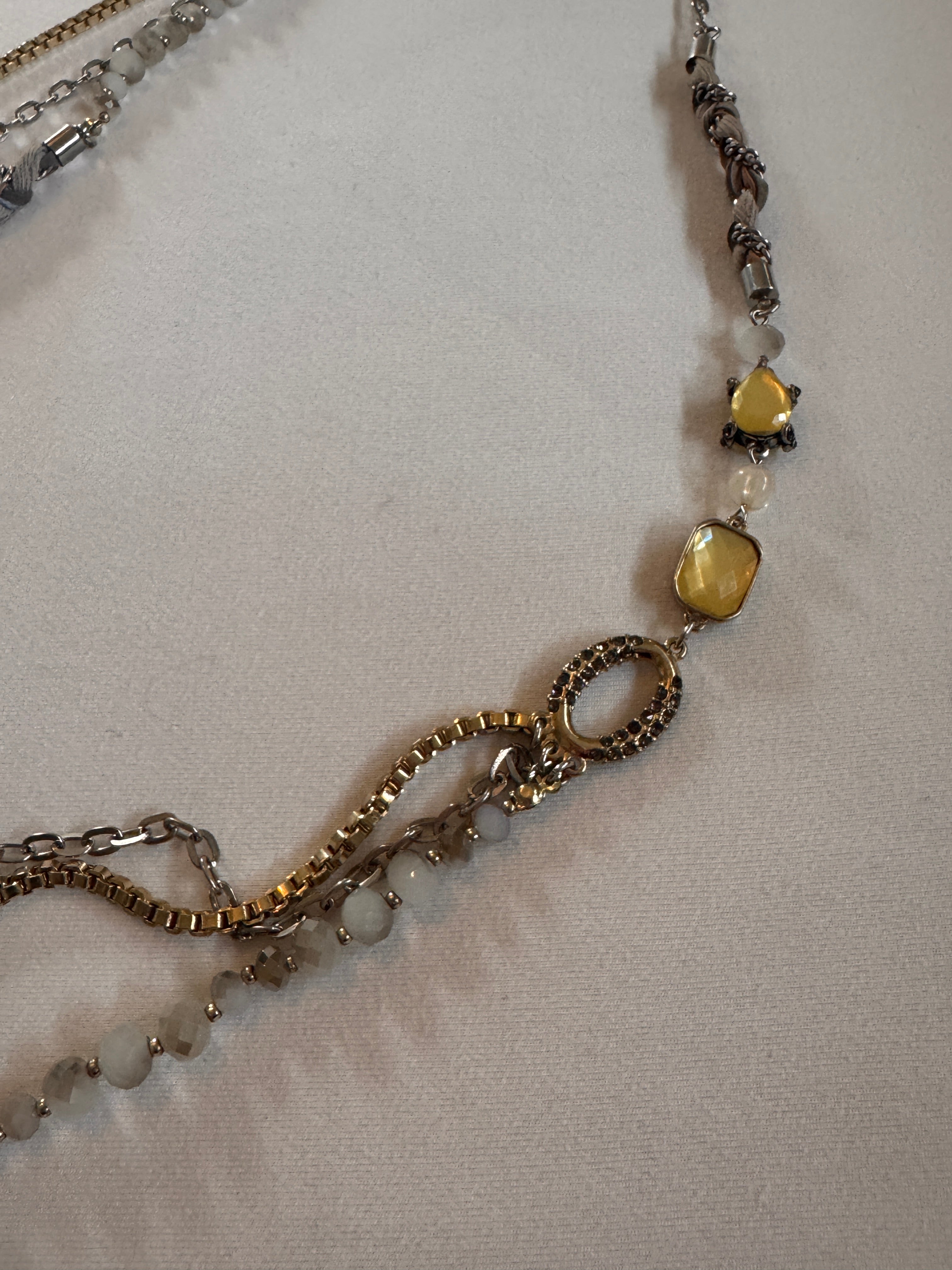 Close-up of a necklace with gold and silver chains on a light fabric background