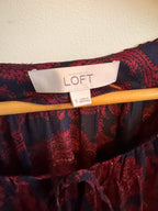 Patterned fabric with a LOFT label on a wooden stick against a neutral background