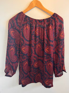 Red and black paisley patterned garment on a beige hanger against a white background