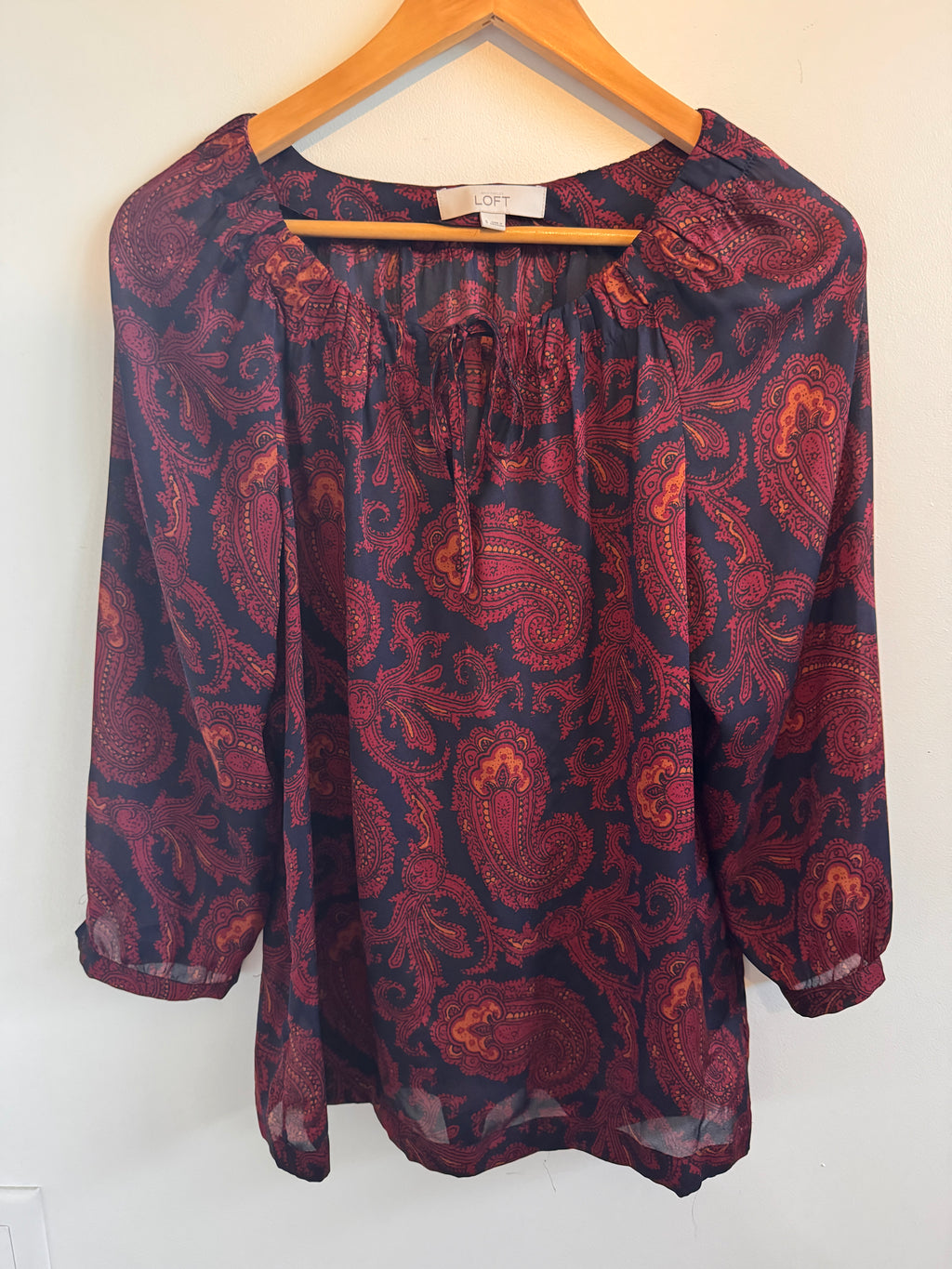 Folded maroon fabric with paisley pattern on a white background