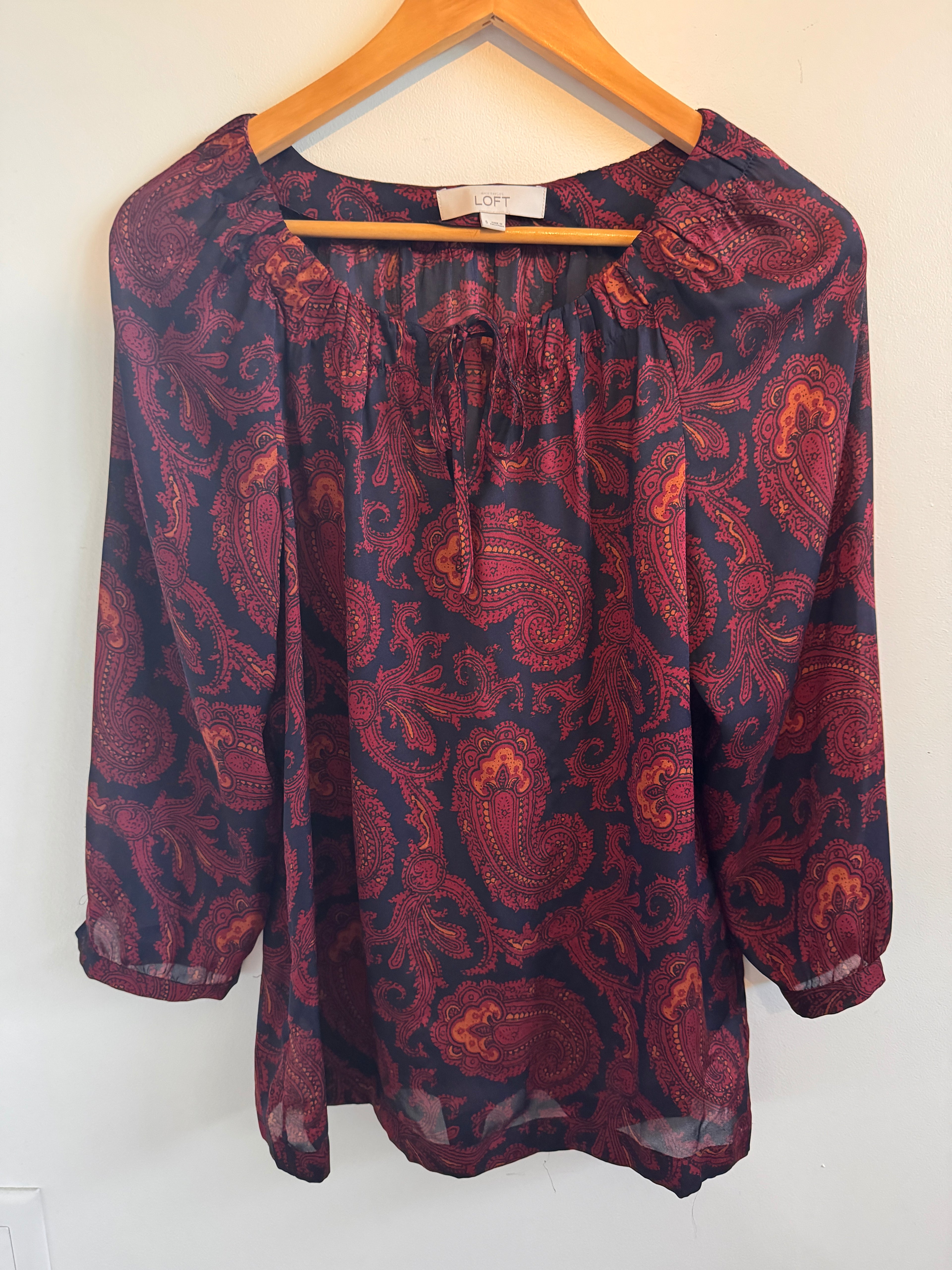 Folded maroon fabric with paisley pattern on a white background