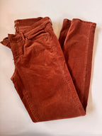 Folded brown pants on a light beige background