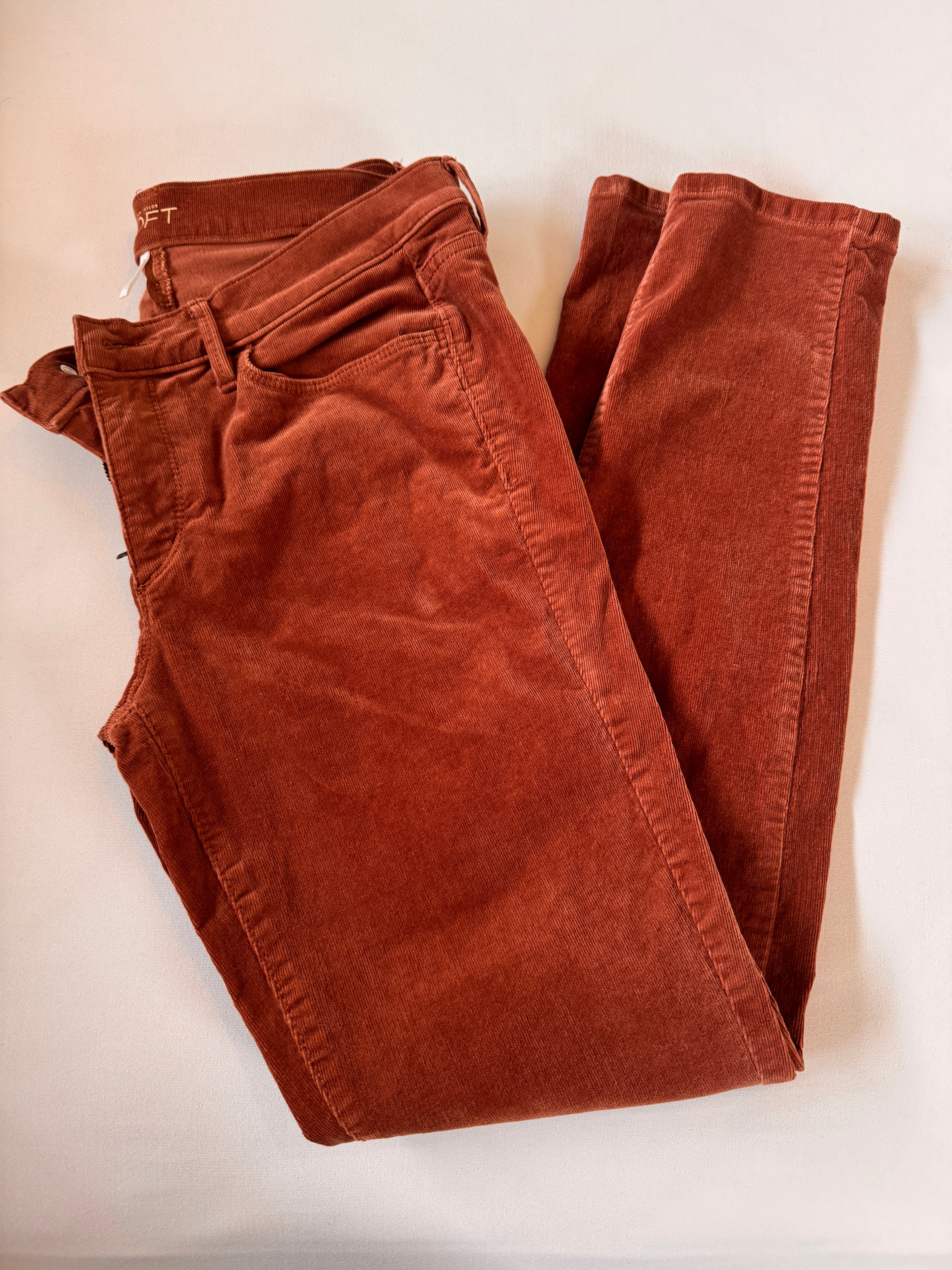 Folded brown pants on a light beige background