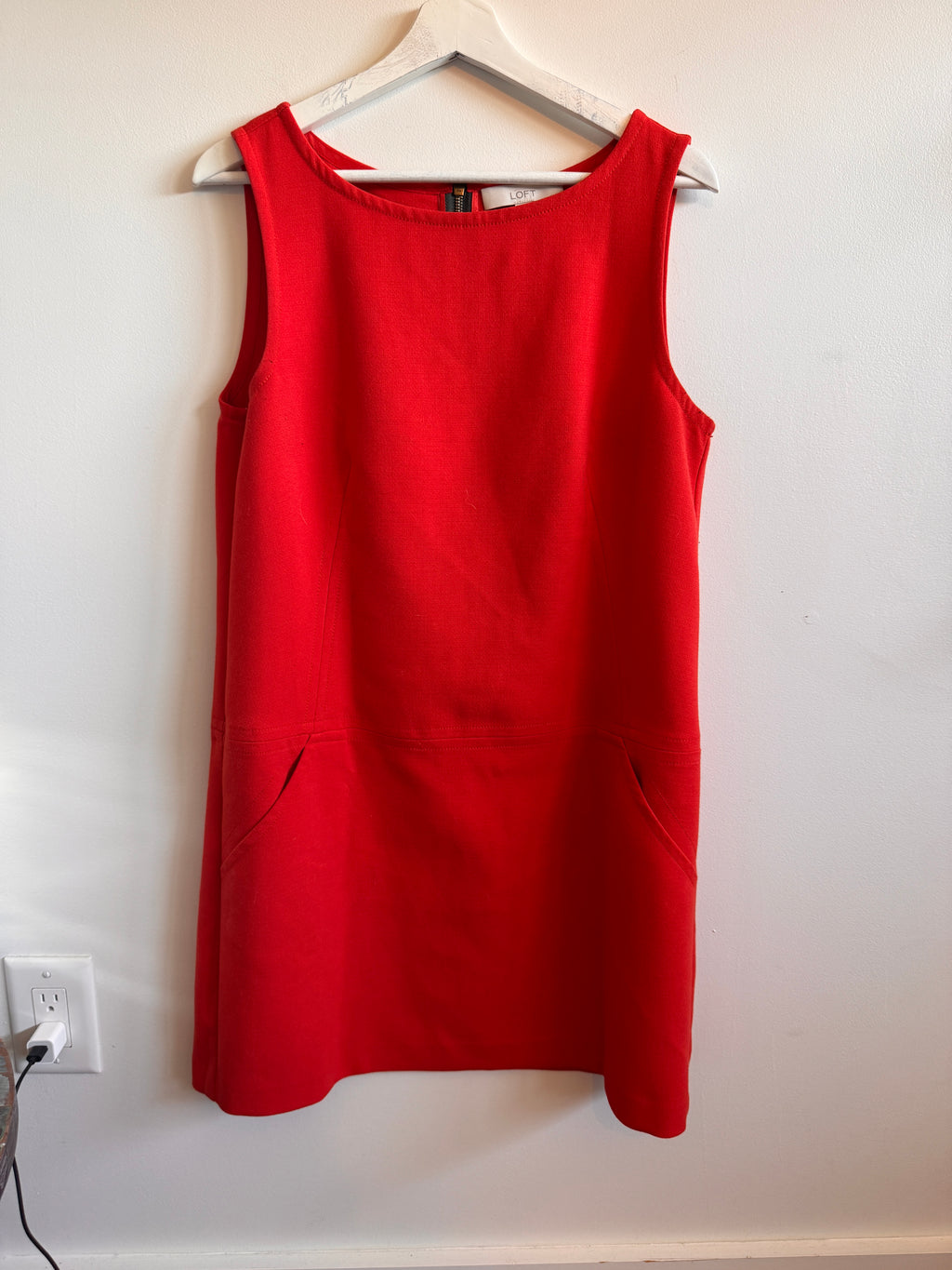 Red dress on a hanger against a white wall