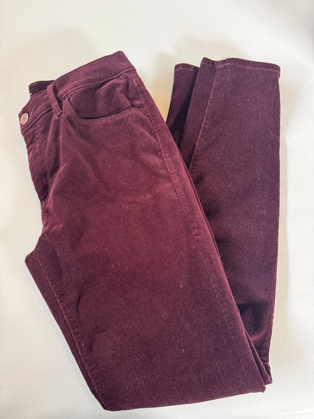 Folded maroon pants on a white background