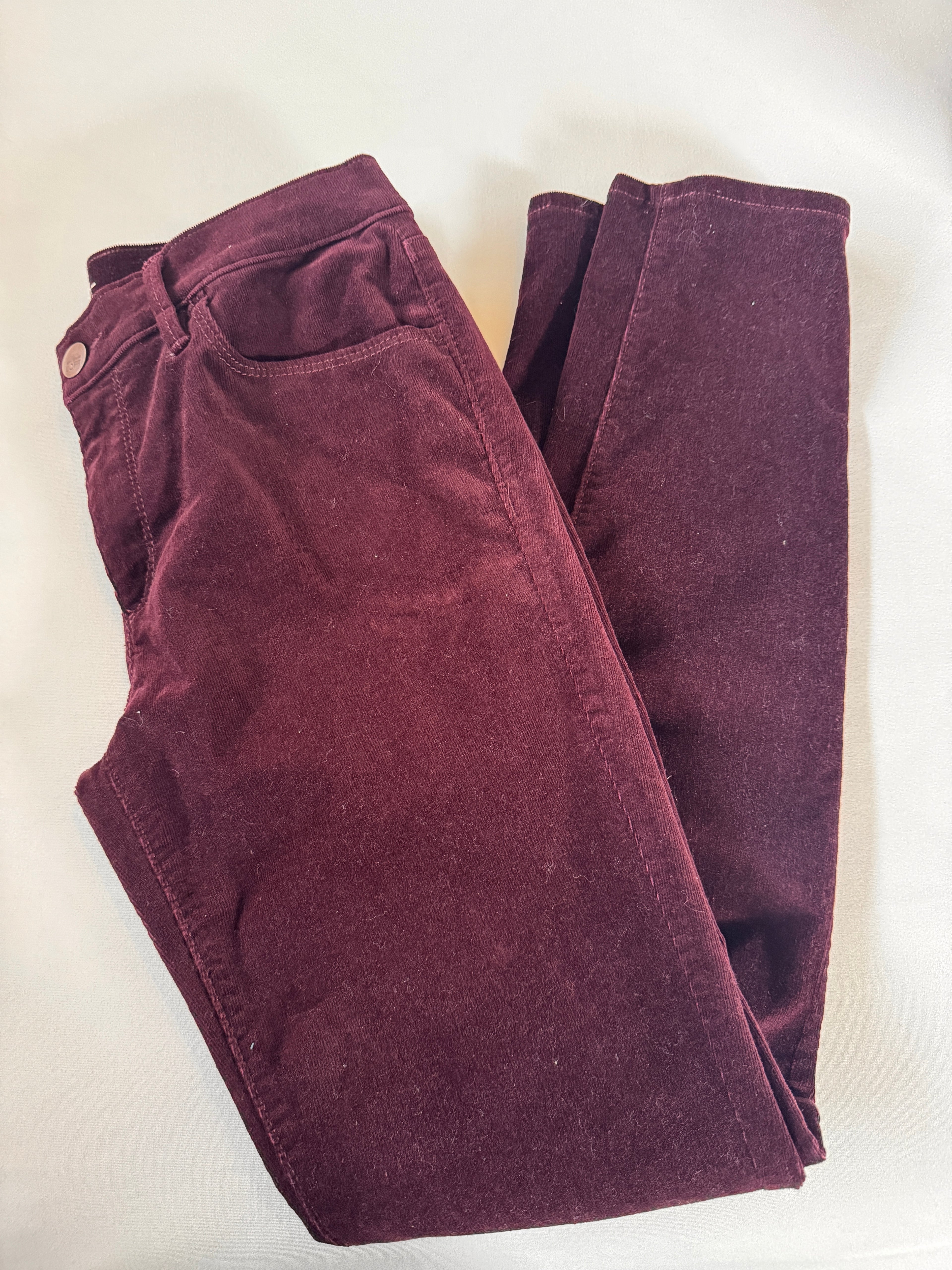 Folded maroon pants on a white background