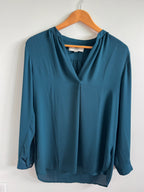 Blue blouse on a wooden hanger against a white background