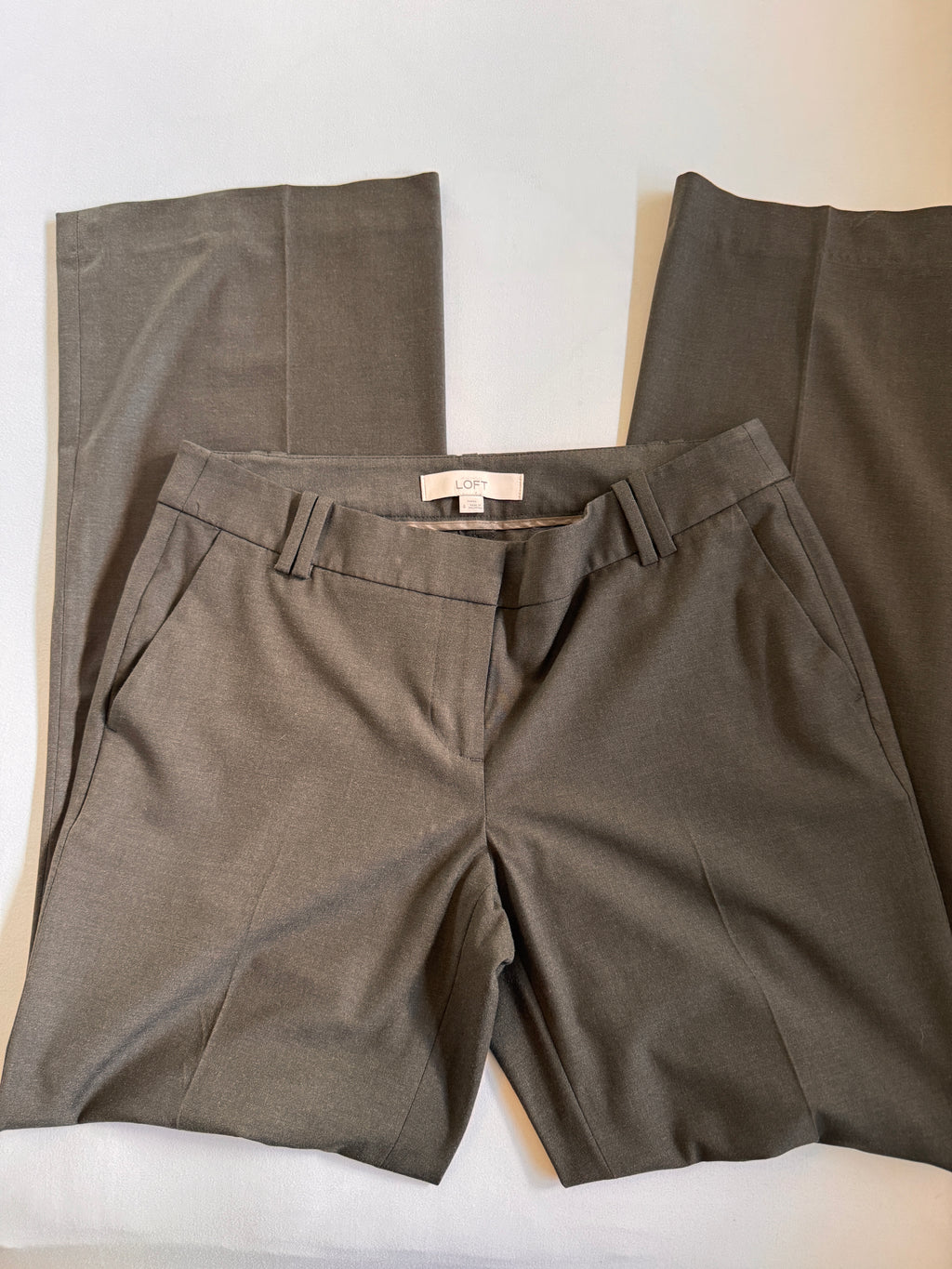 Greige pants with a visible brand tag on a white surface