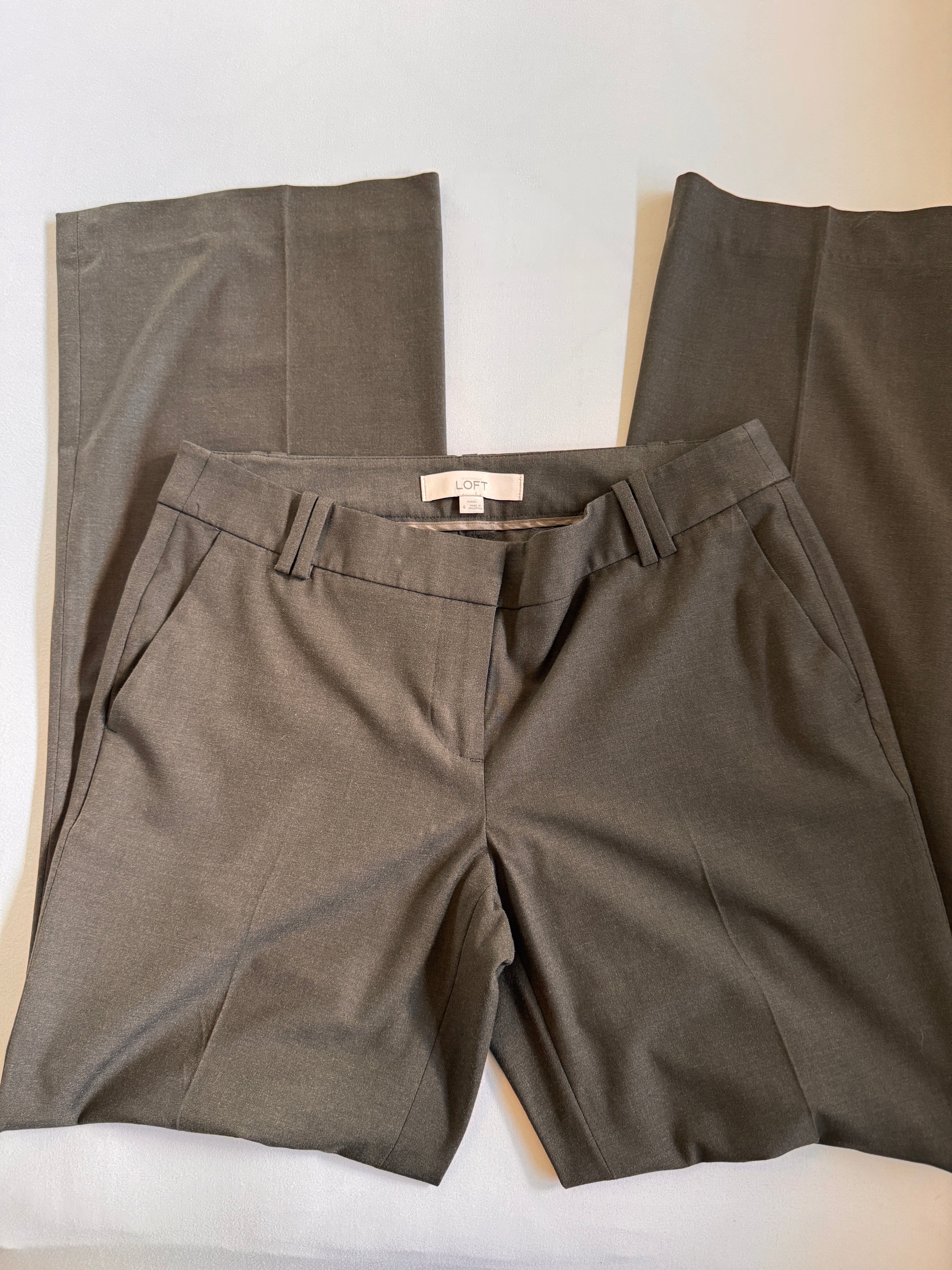 Greige pants with a visible brand tag on a white surface