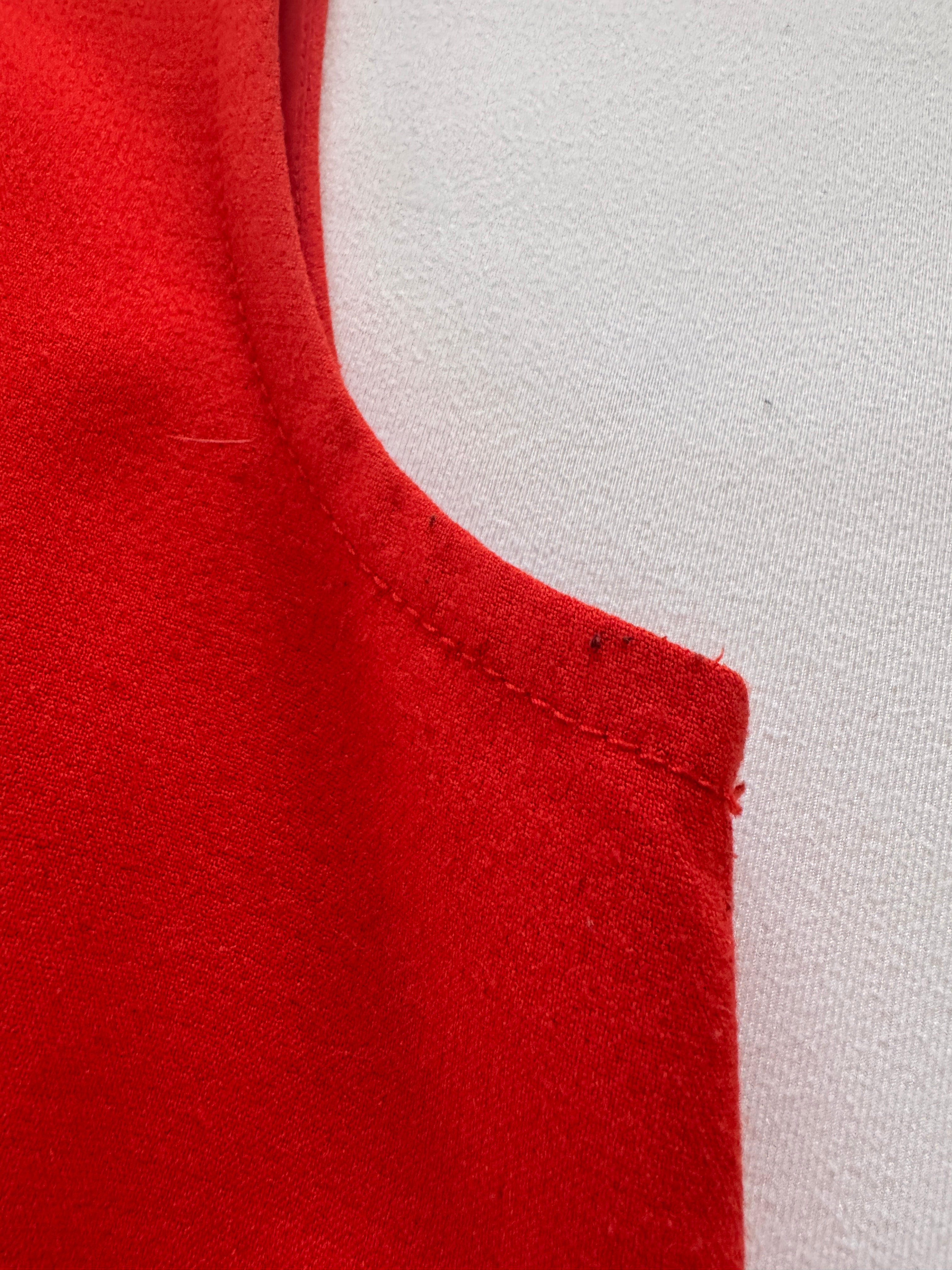 Close-up of red fabric with a visible seam on a light gray background
