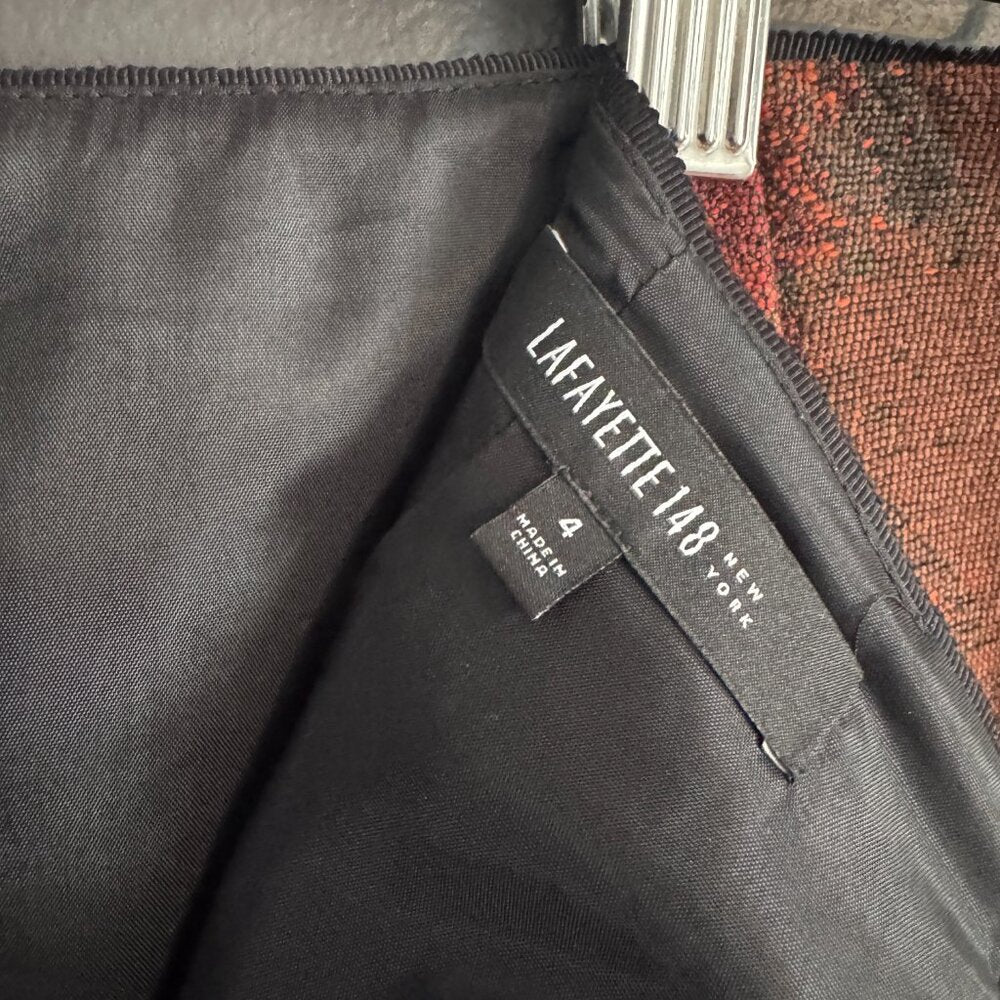 Close-up of a gray garment with a Lafayette 148 New York tag on a textured surface.