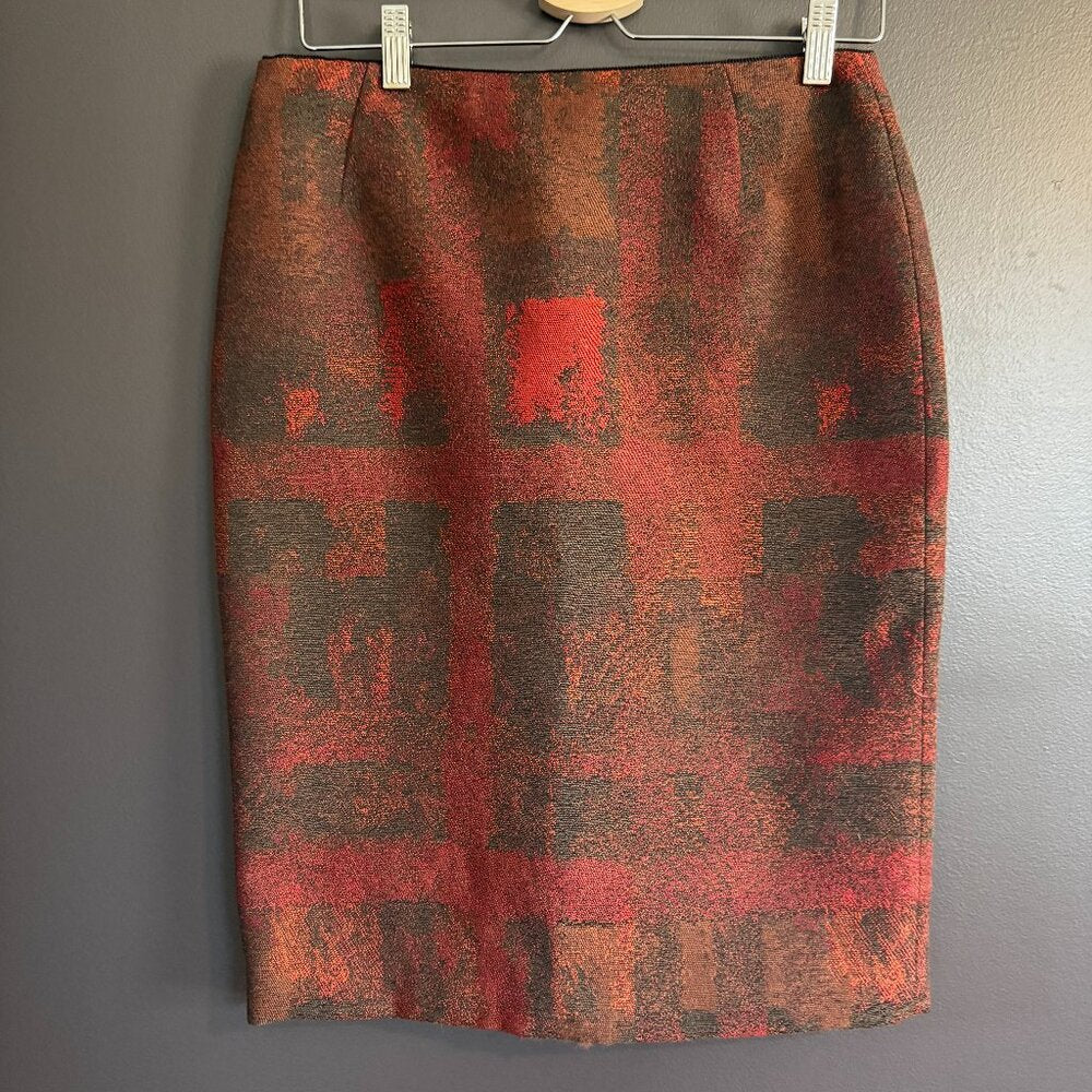 Red and brown patterned skirt on a hanger against a gray background