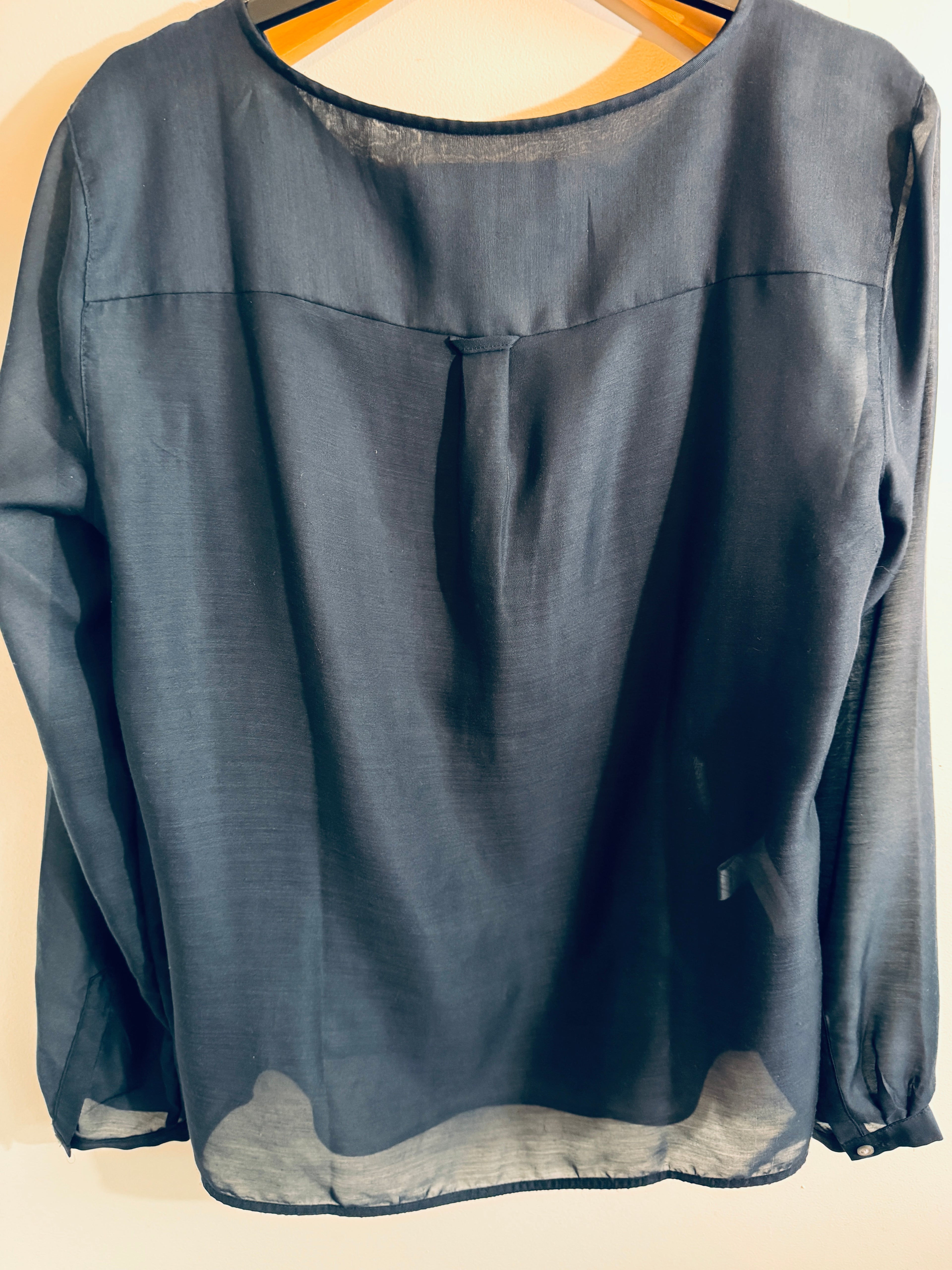 Dark blue blouse on a hanger against a beige background