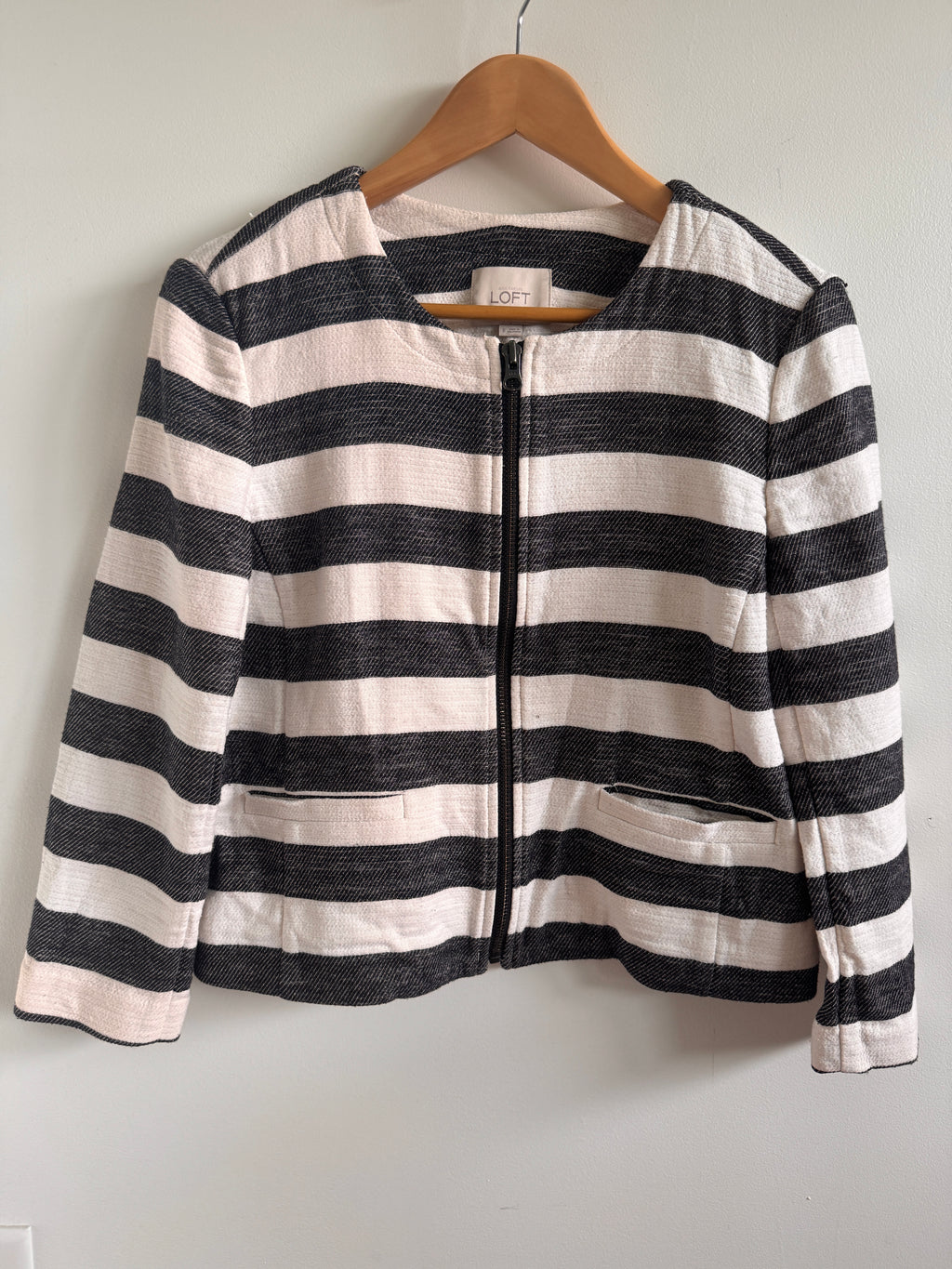 Black and white striped fabric on a wooden hanger against a light gray background