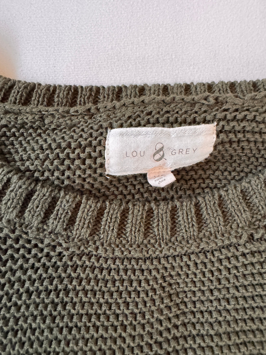 Close-up of a knitted fabric with a brand label on a plain background