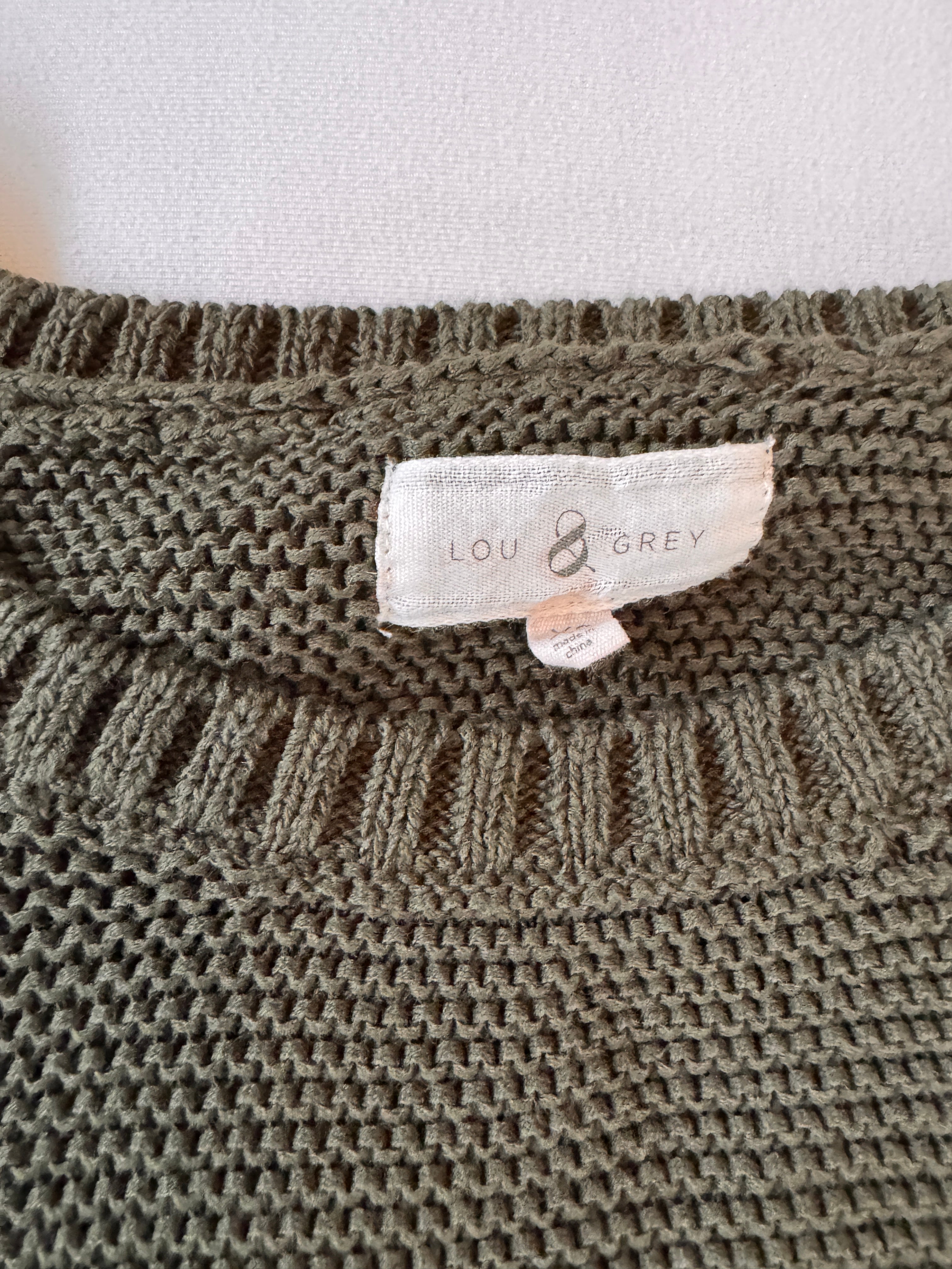 Close-up of a knitted fabric with a brand label on a plain background